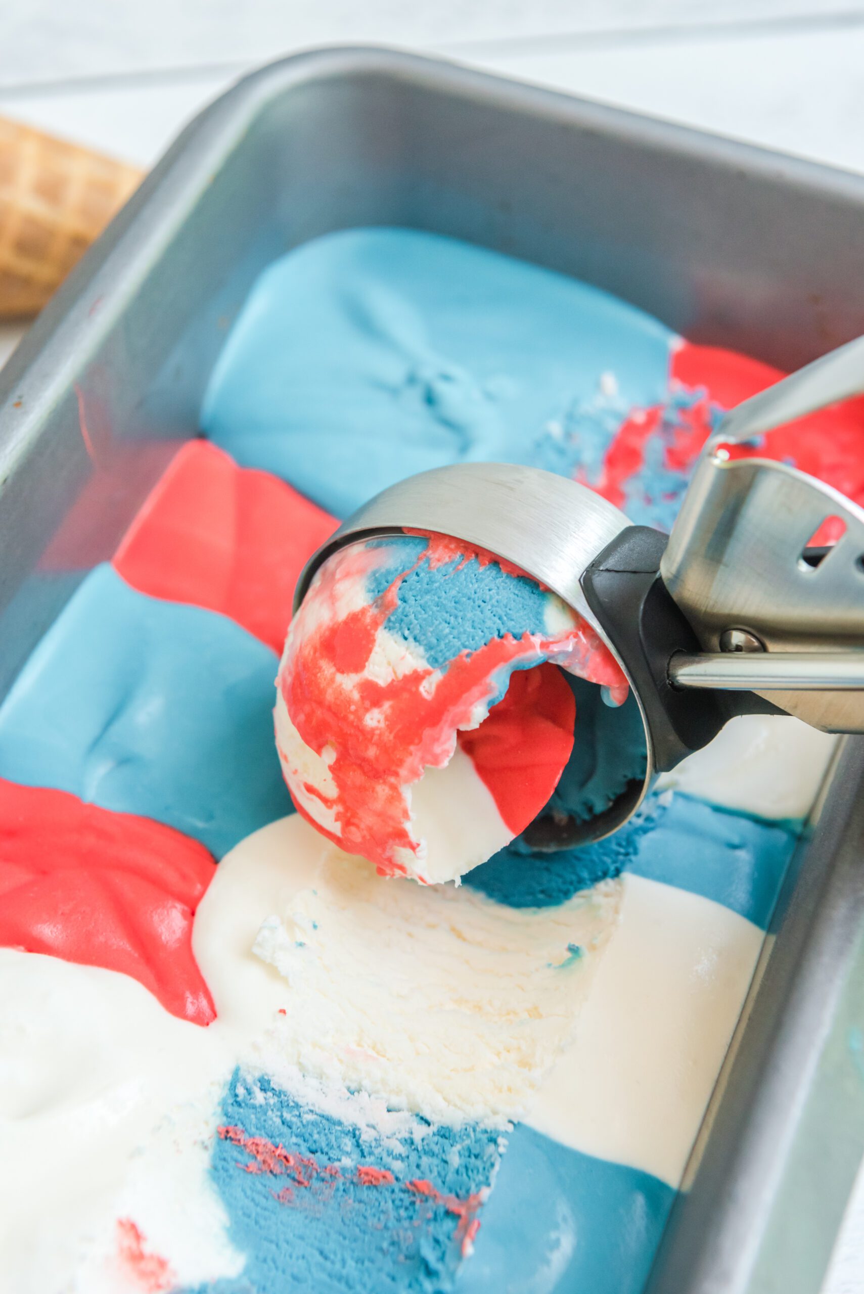 Red, White & Blue Ice Cream in a ice cream tin pan with an ice cream scoop in it