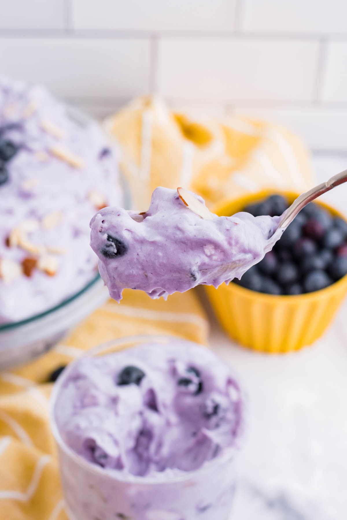 Blueberry Fluff Salad in a clear glass mini trifle with a spoon lifting up a big bite