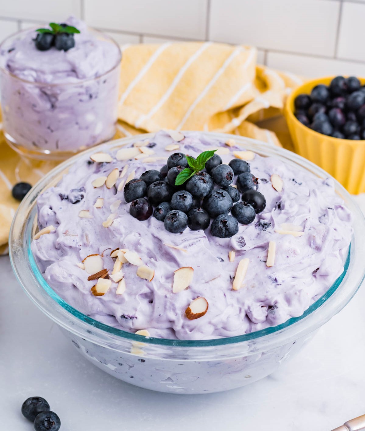 Blueberry Fluff Salad in a clear glass serving bowl topped with blueberries and chopped almonds
