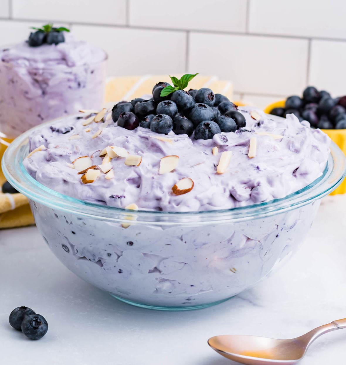 Blueberry Fluff Salad in a clear glass serving bowl topped with fresh blueberries
