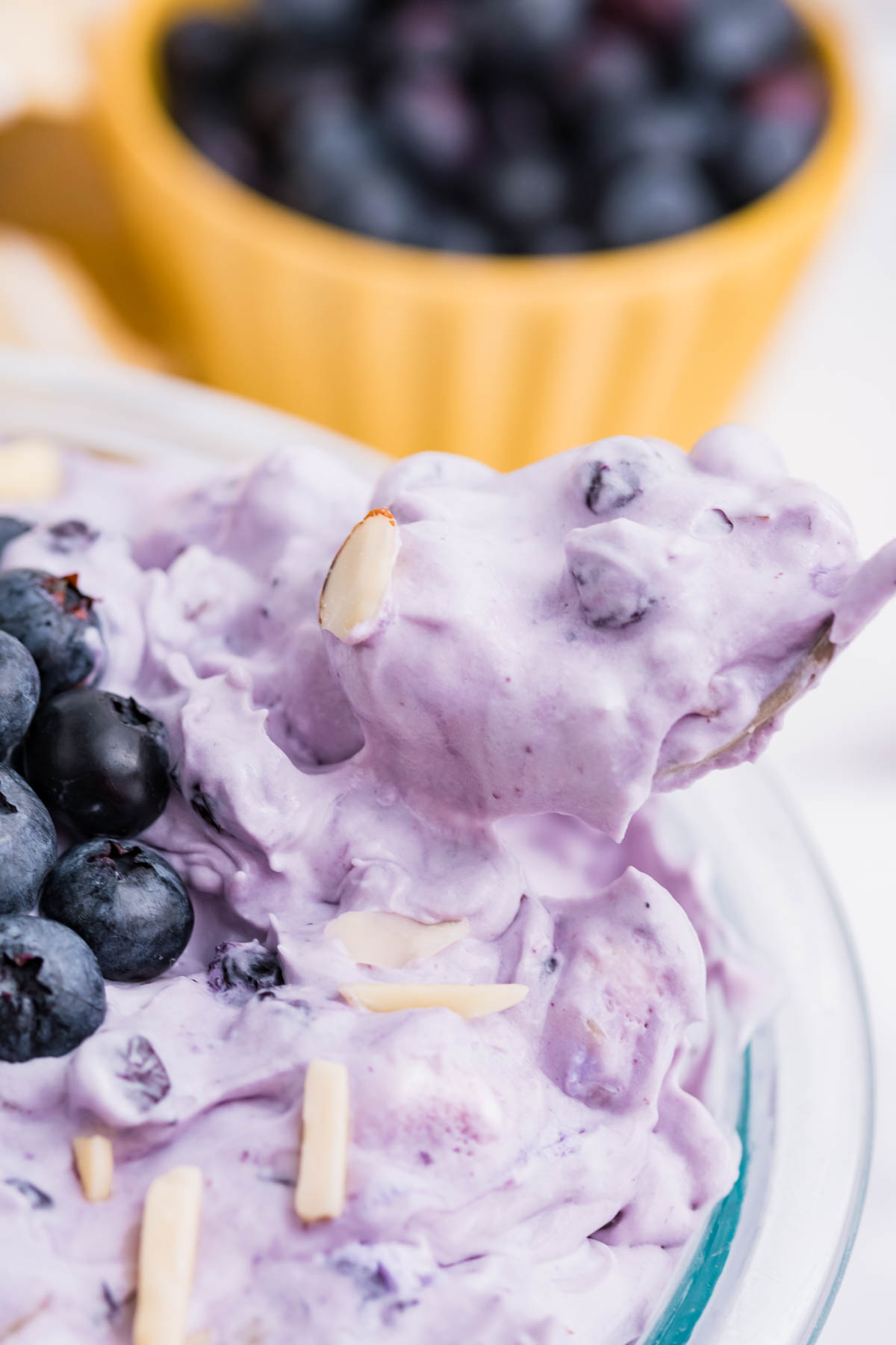 Blueberry Fluff Salad in a clear glass bowl with a spoon lifting it out