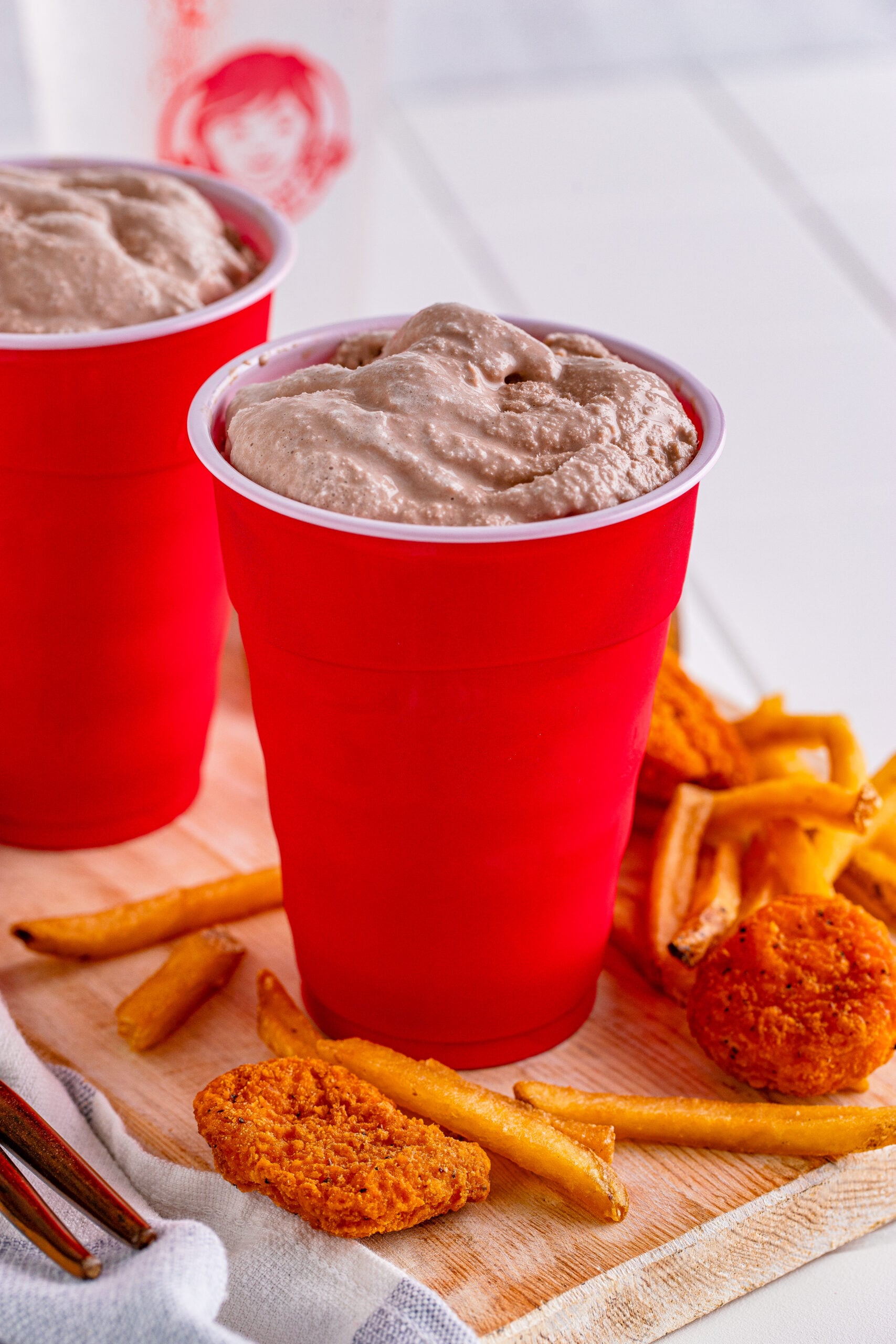 Wendys Frosty homemade in a red solo cup surrounded by nuggets and fries
