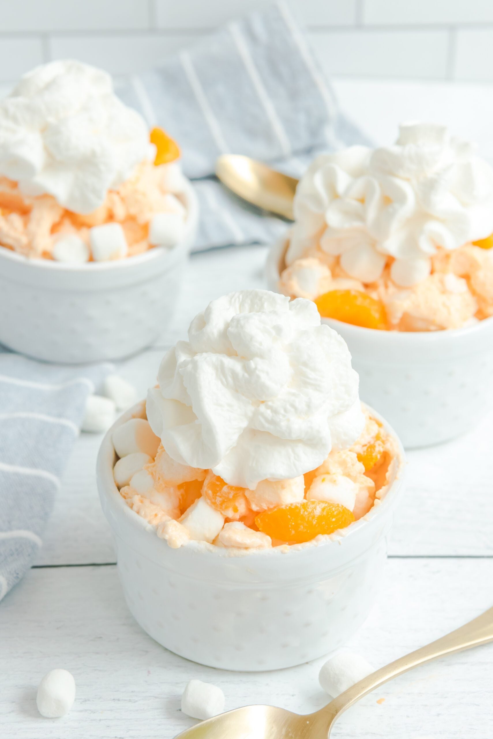 Orange Creamsicle Salad in a white bowl topped with whipped cream