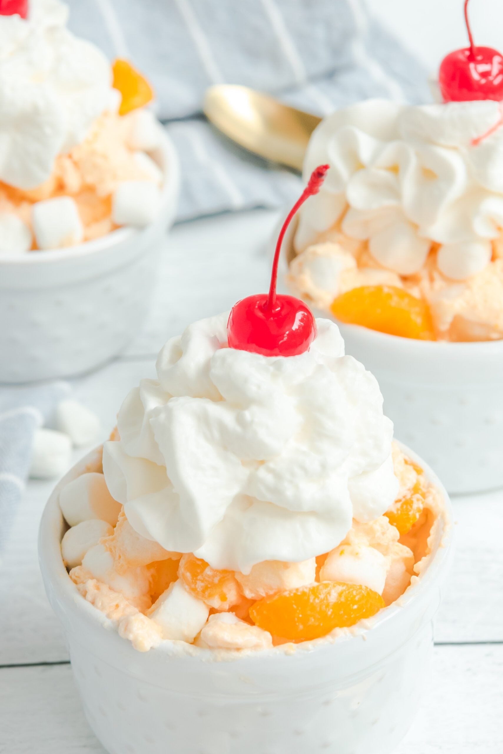Orange Creamsicle Salad in a white bowl topped with whipped cream close up