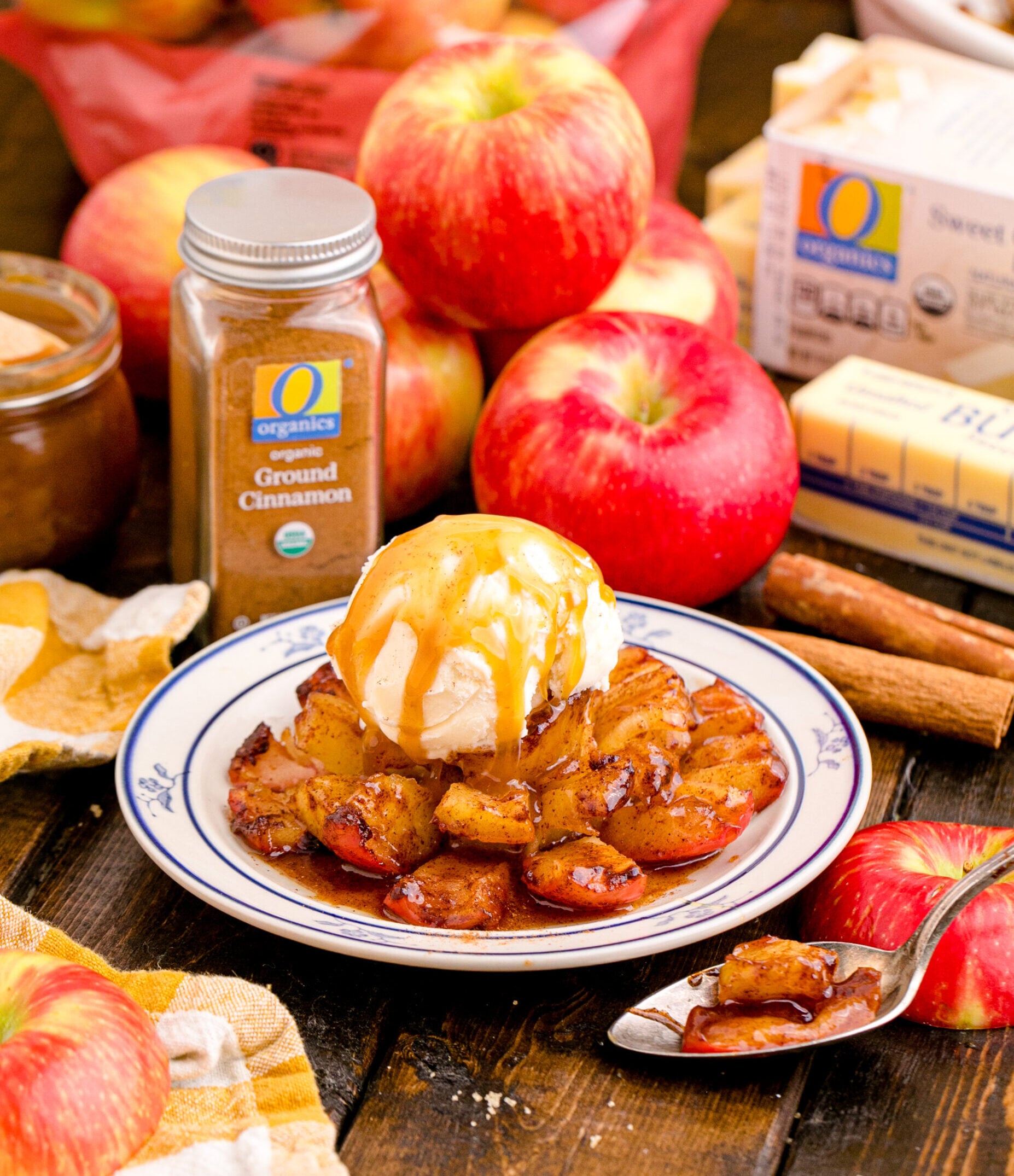Oven Baked Bloomin Apples on a white plate topped with ice cream on a wood table with apples in the background