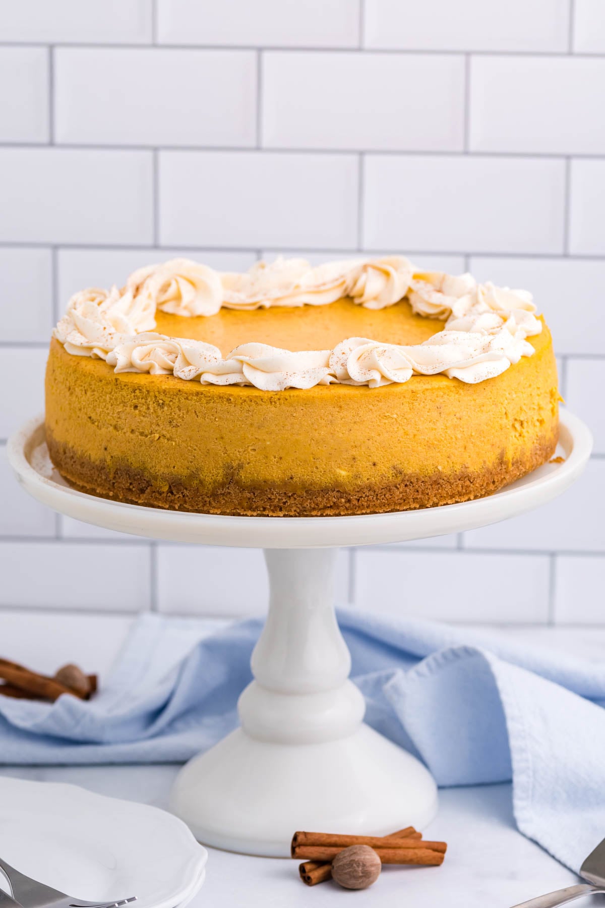 Pumpkin Cheesecake far away shot of it sitting on a white cake stand
