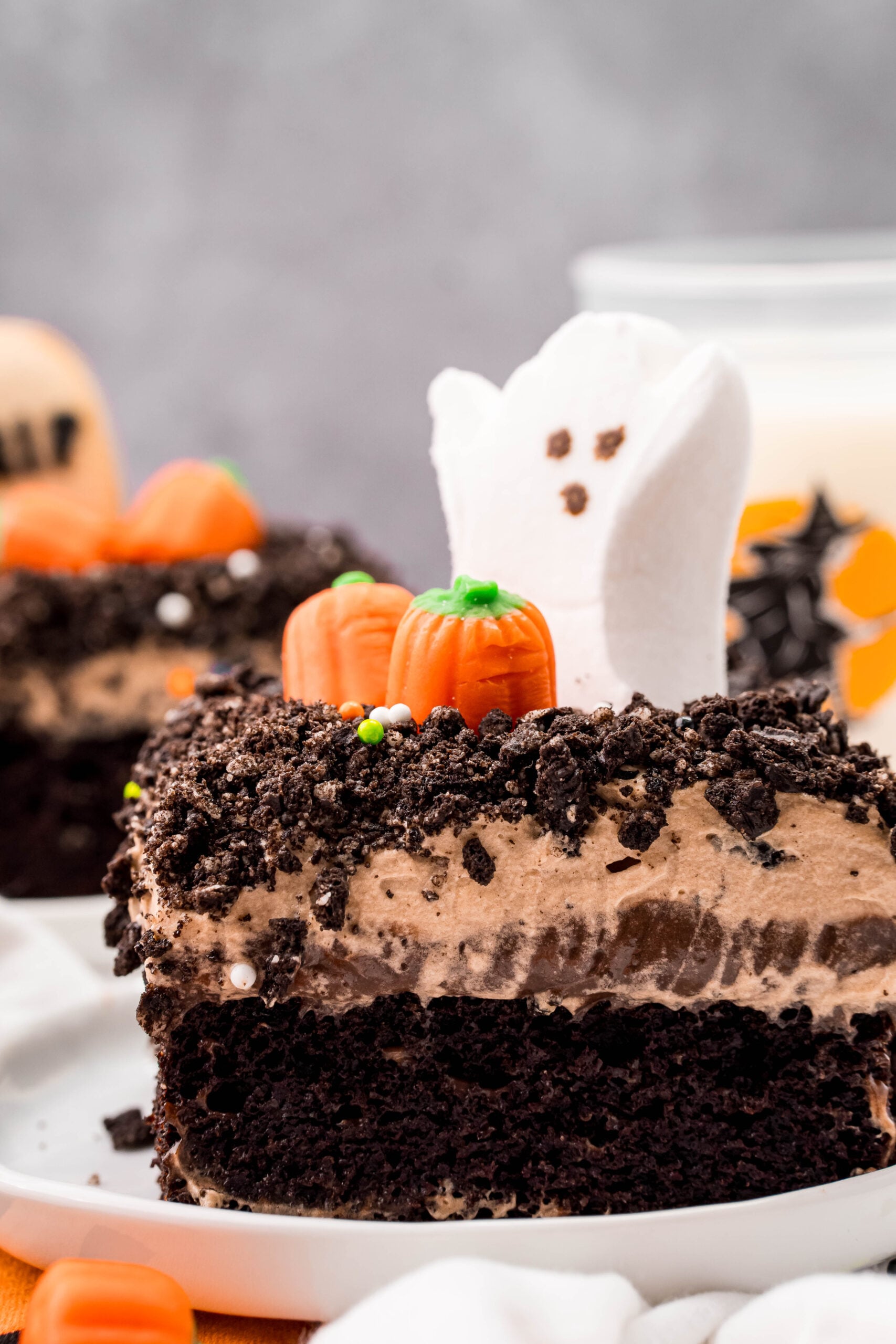 Halloween Dirt Cake slice on a white plate with a ghost marshmallow peep on top