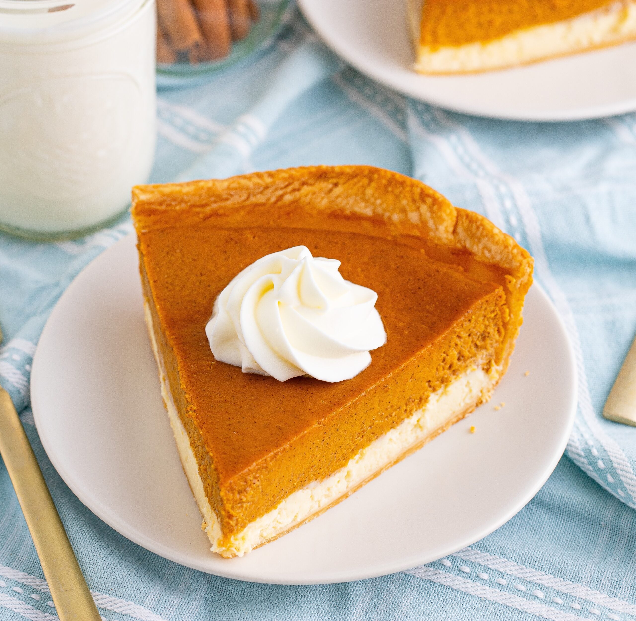 Pumpkin Pie Cheesecake slice on a white plate with a glass of milk next to it