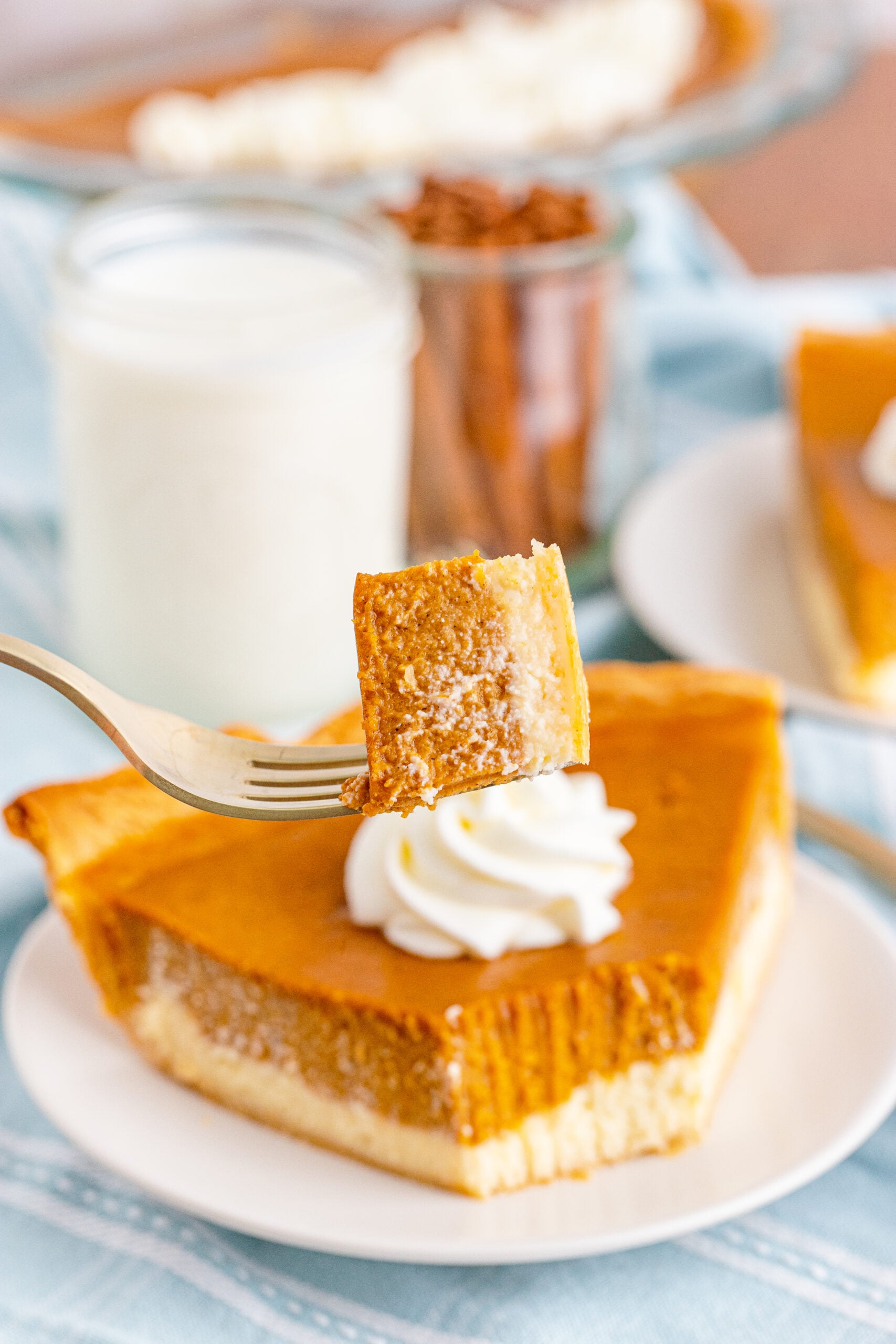 Pumpkin Pie Cheesecake slice on a white plate with a fork lifting up a bite