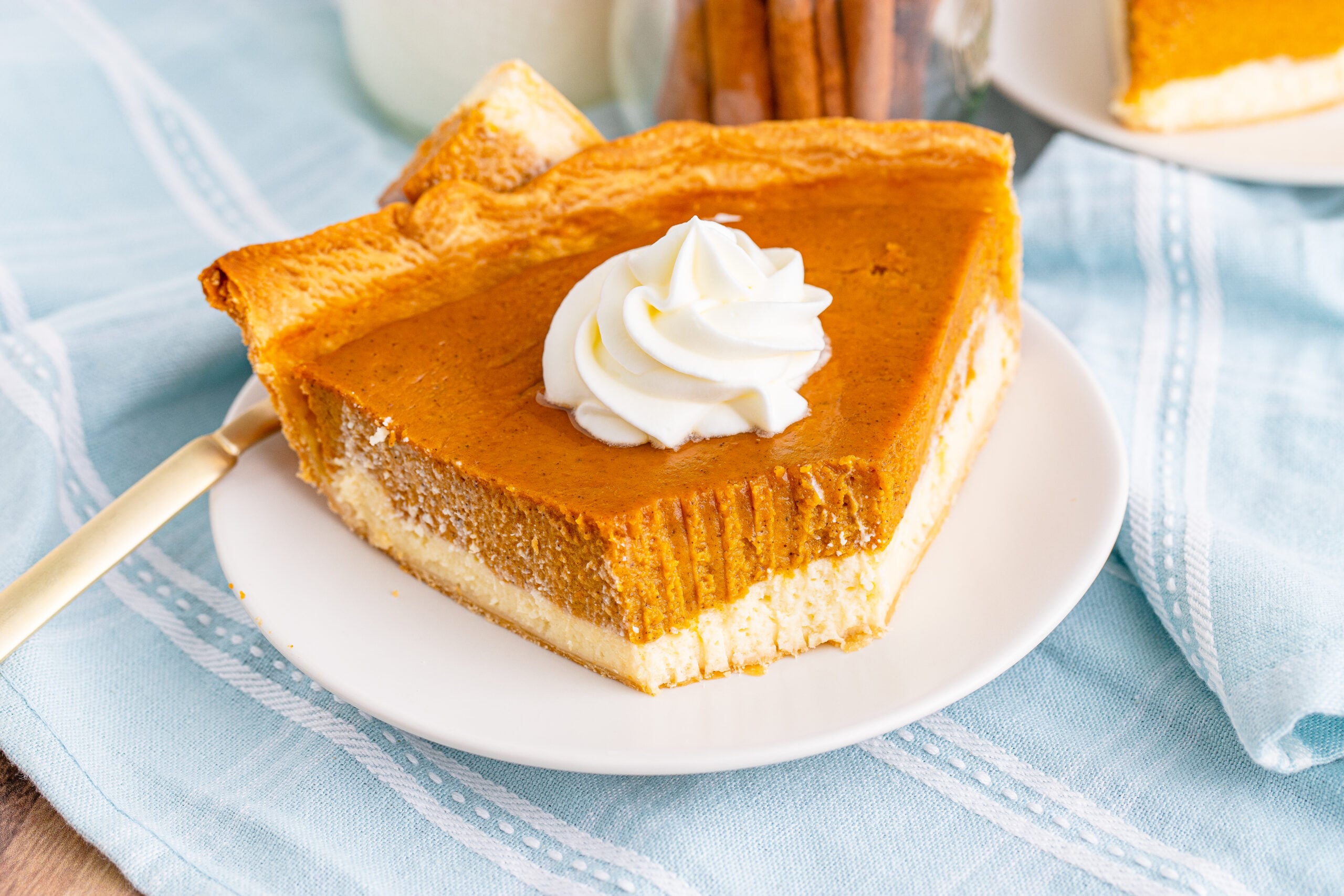 Pumpkin Pie Cheesecake slice on a white plate with whipped cream on top