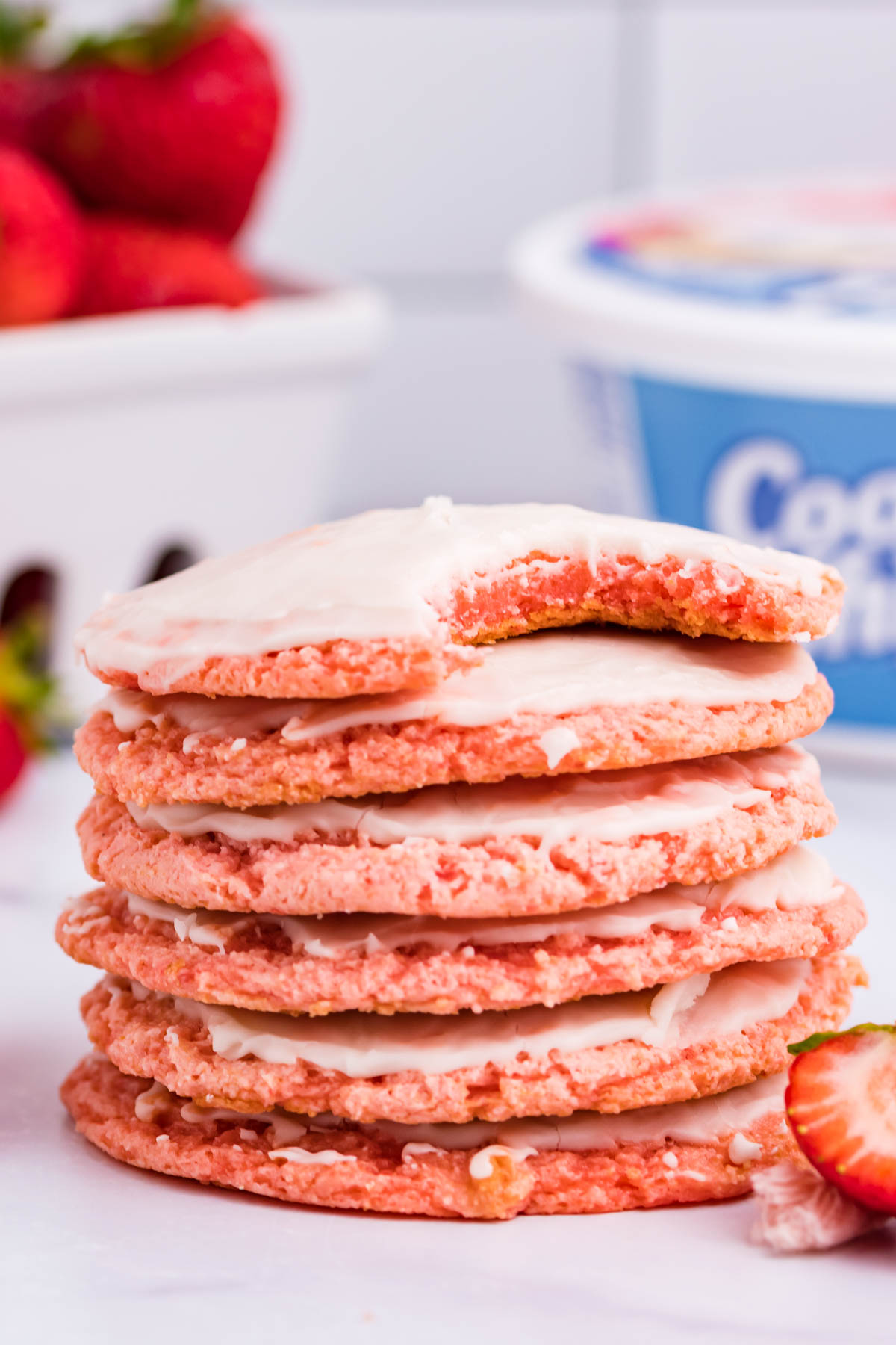 a stack of Strawberry Cool Whip Cookies with the top cookie missing a bite