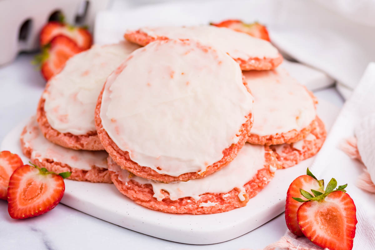 Strawberry Cool Whip Cookies topped with strawberry icing on a white plate