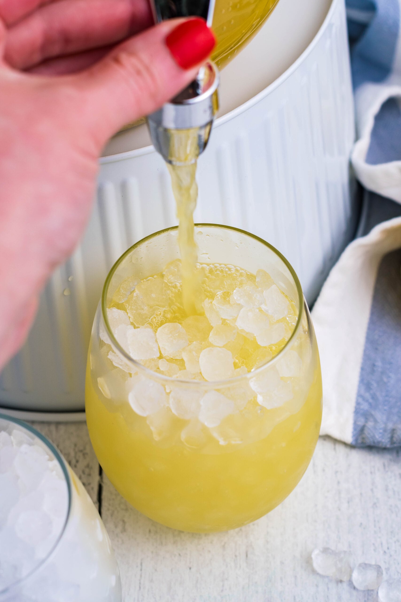 Pineapple Lemonade being poured into a clear glass filled with crushed ice
