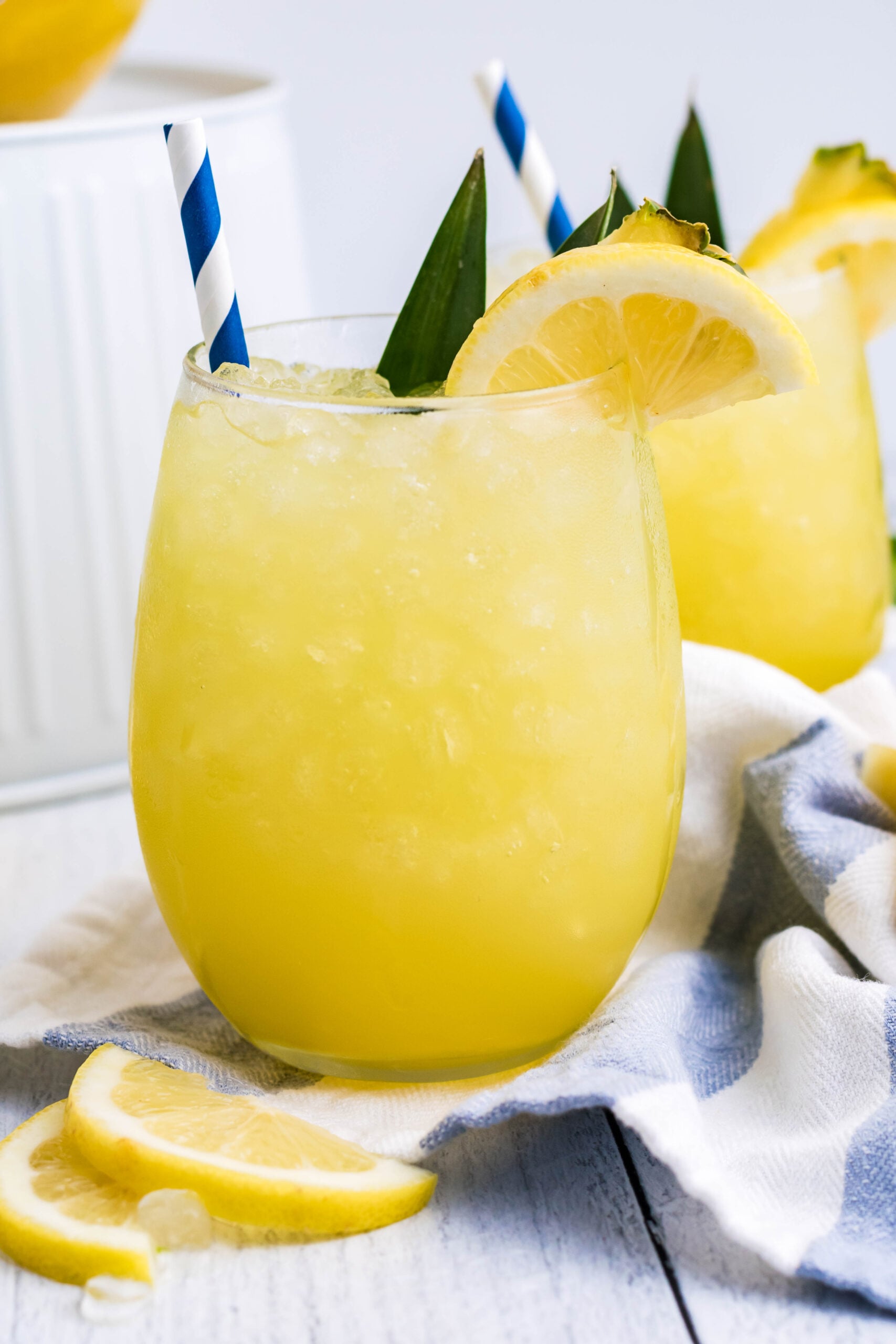 Pineapple Lemonade in a clear glass with ice and a sliced lemon