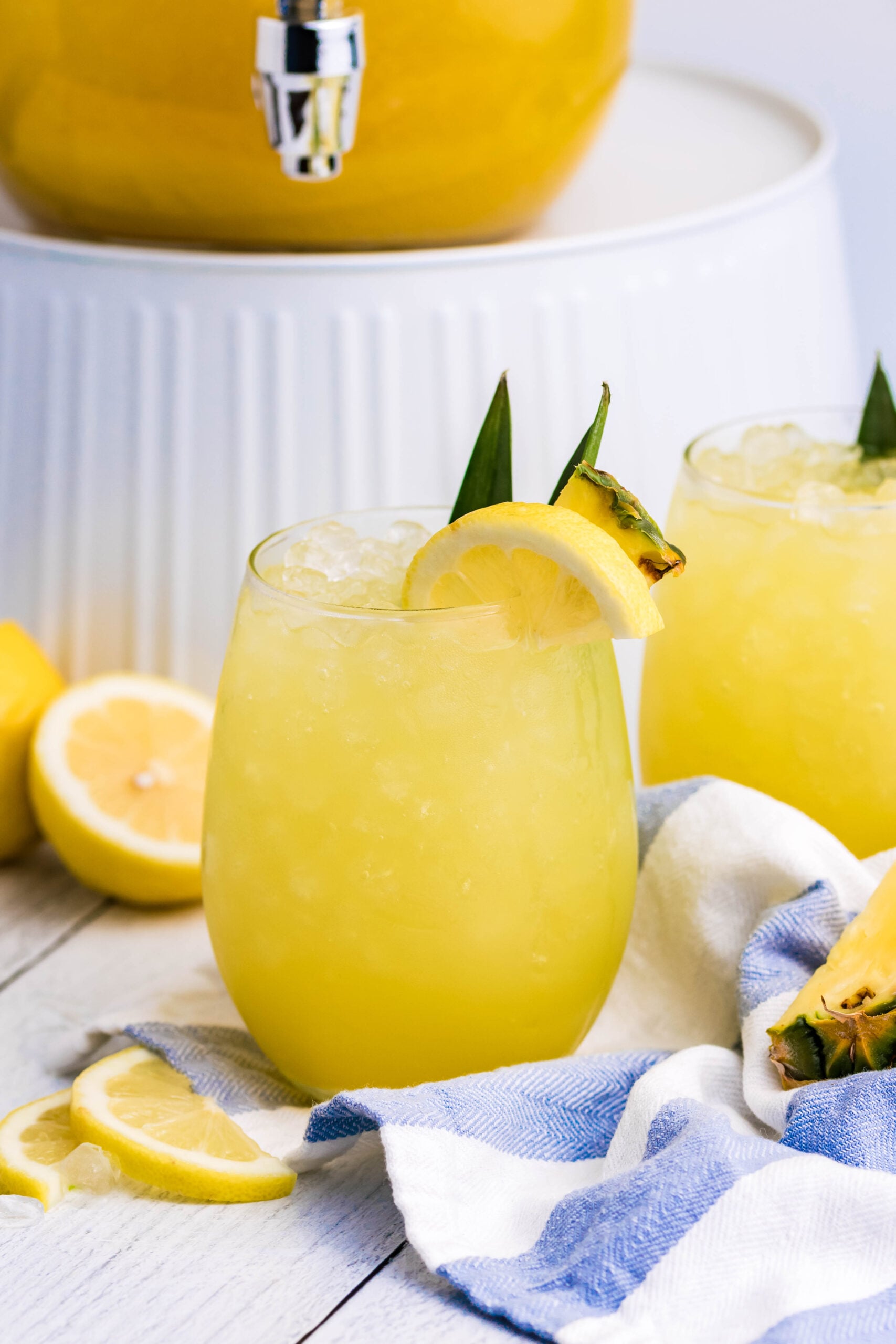 Pineapple Lemonade in a clear glass with ice on a white wood table