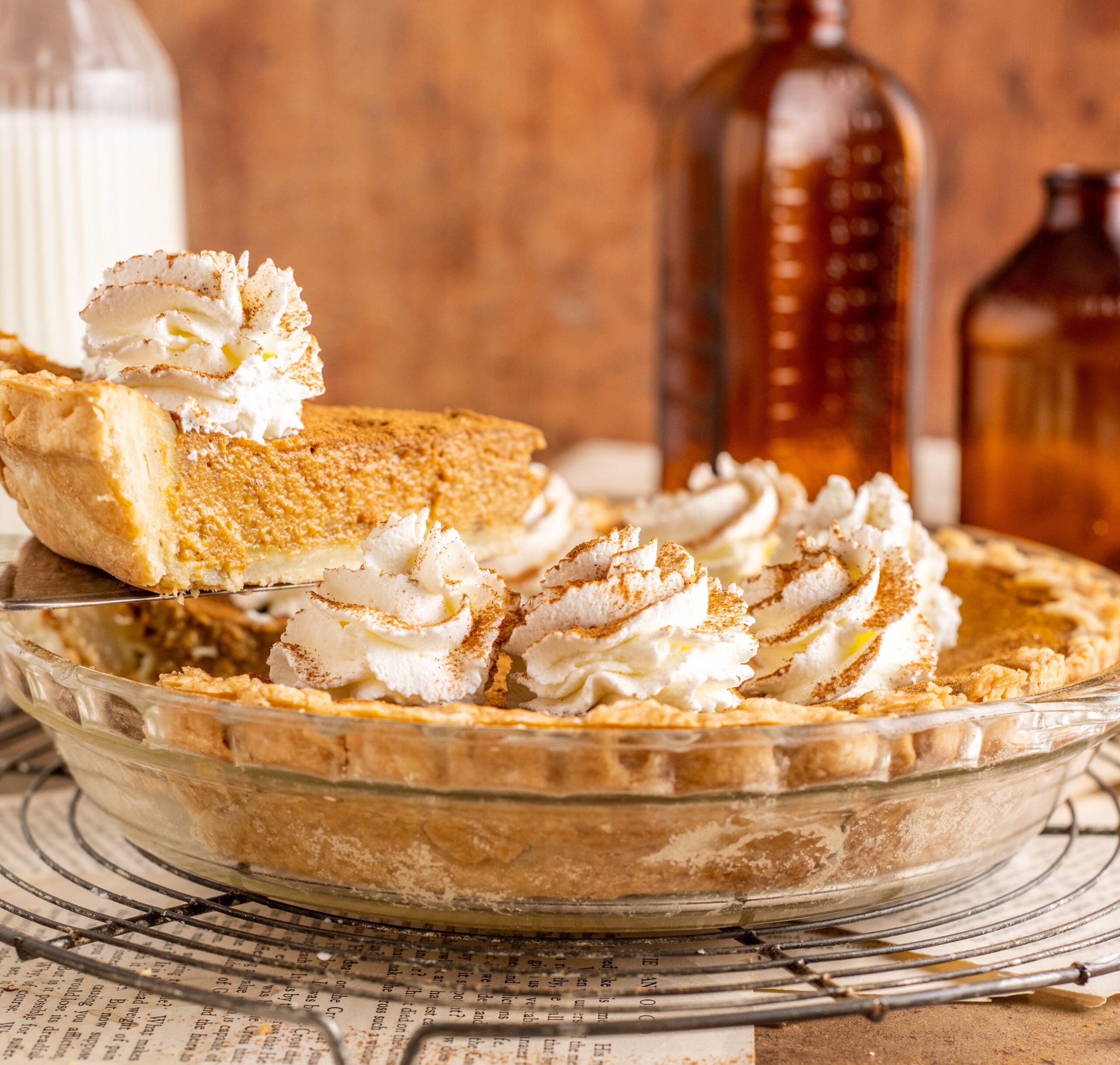 Pumpkin Custard Pie in a clear pie dish with a slice being lifted up