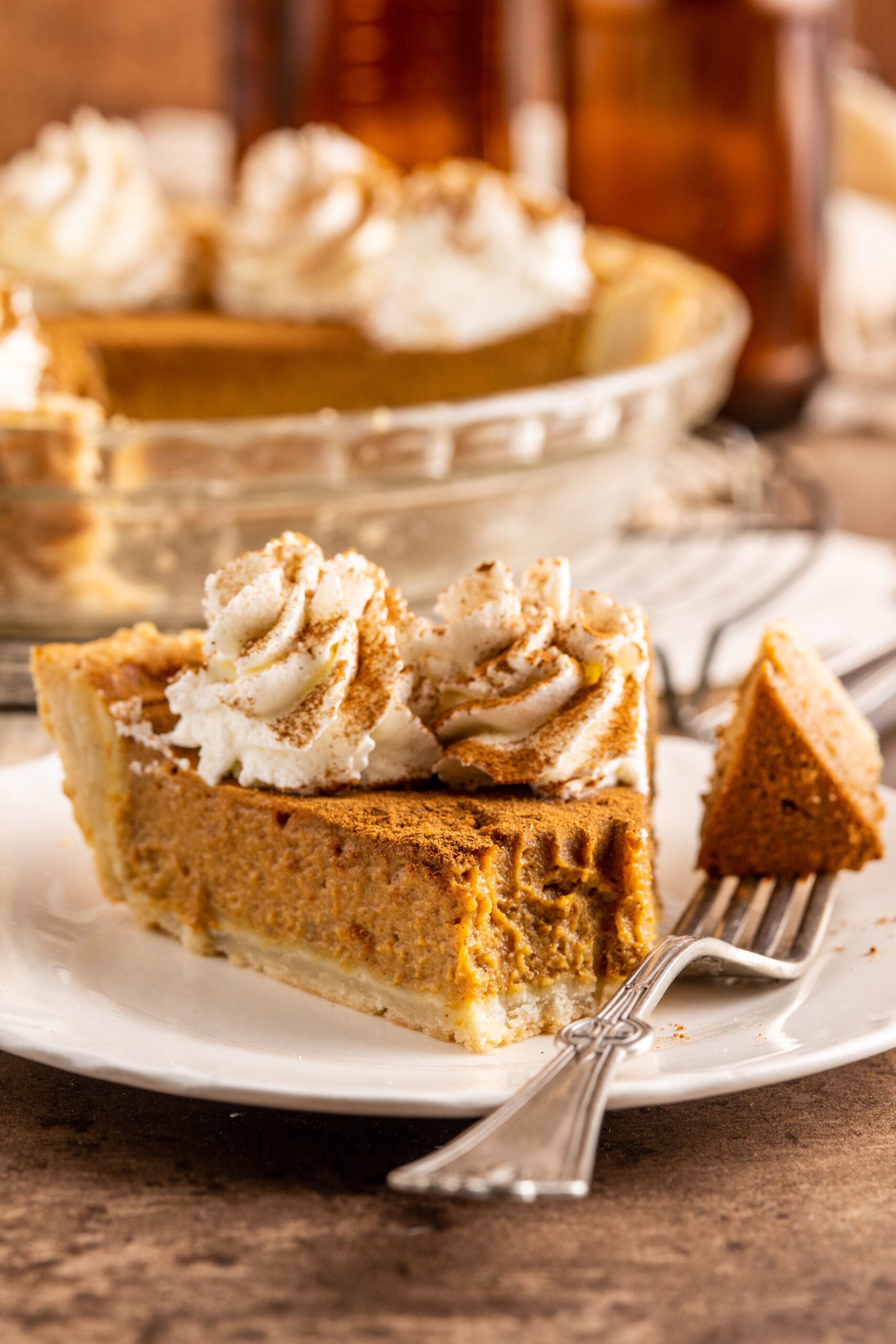 Pumpkin Custard Pie slice on a white plate with a bite on a fork