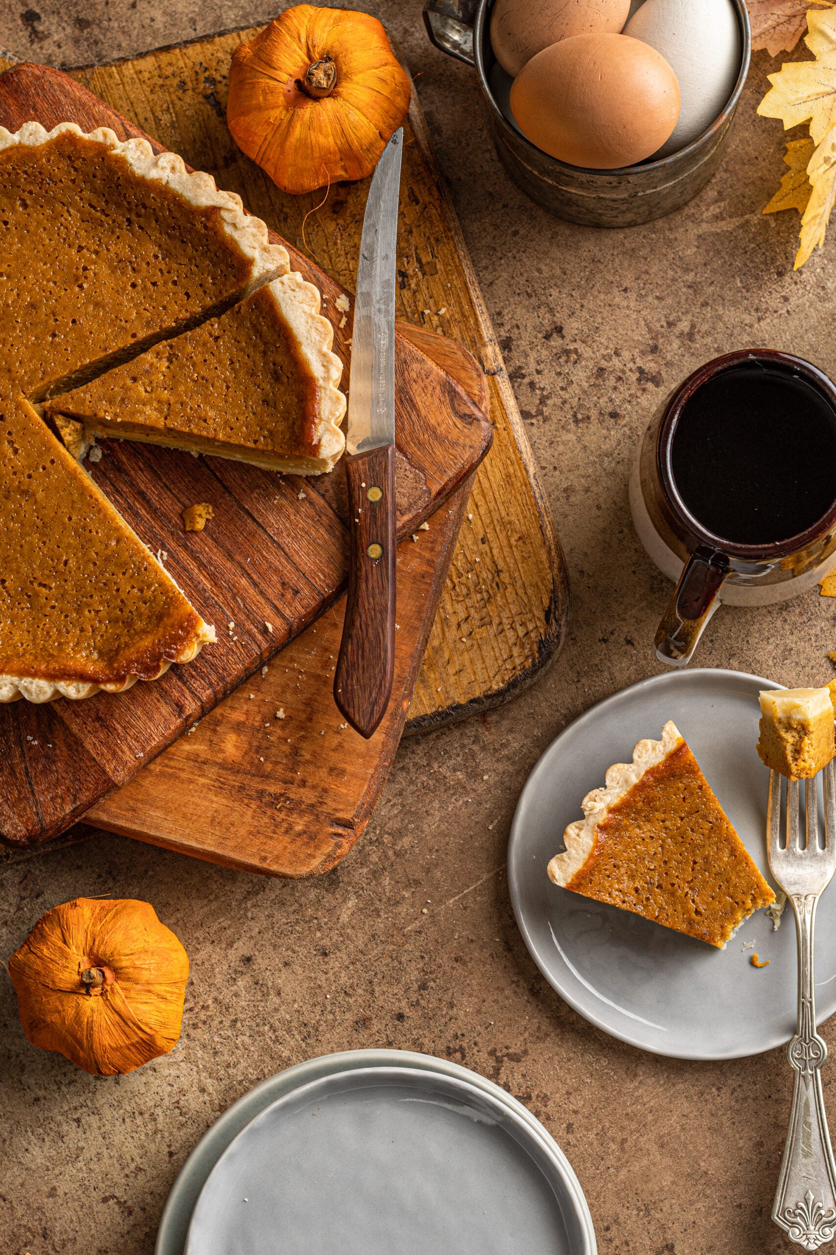 Overhead shot of Pumpkin Pie Tart with a mug of coffee in the photo with the slice on a gray plate