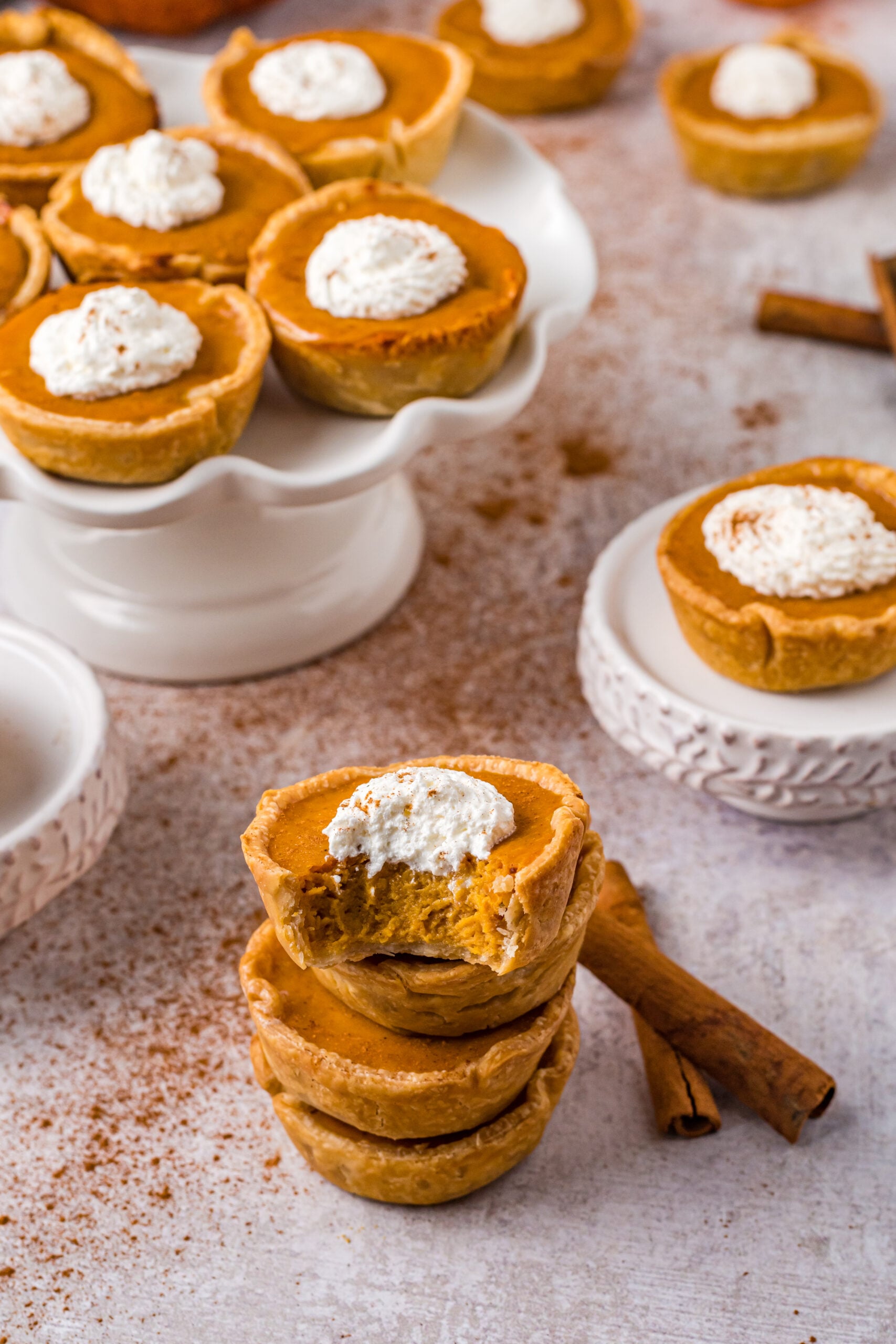Mini Pumpkin Pies stacked with a bite missing and topped with whipped cream 