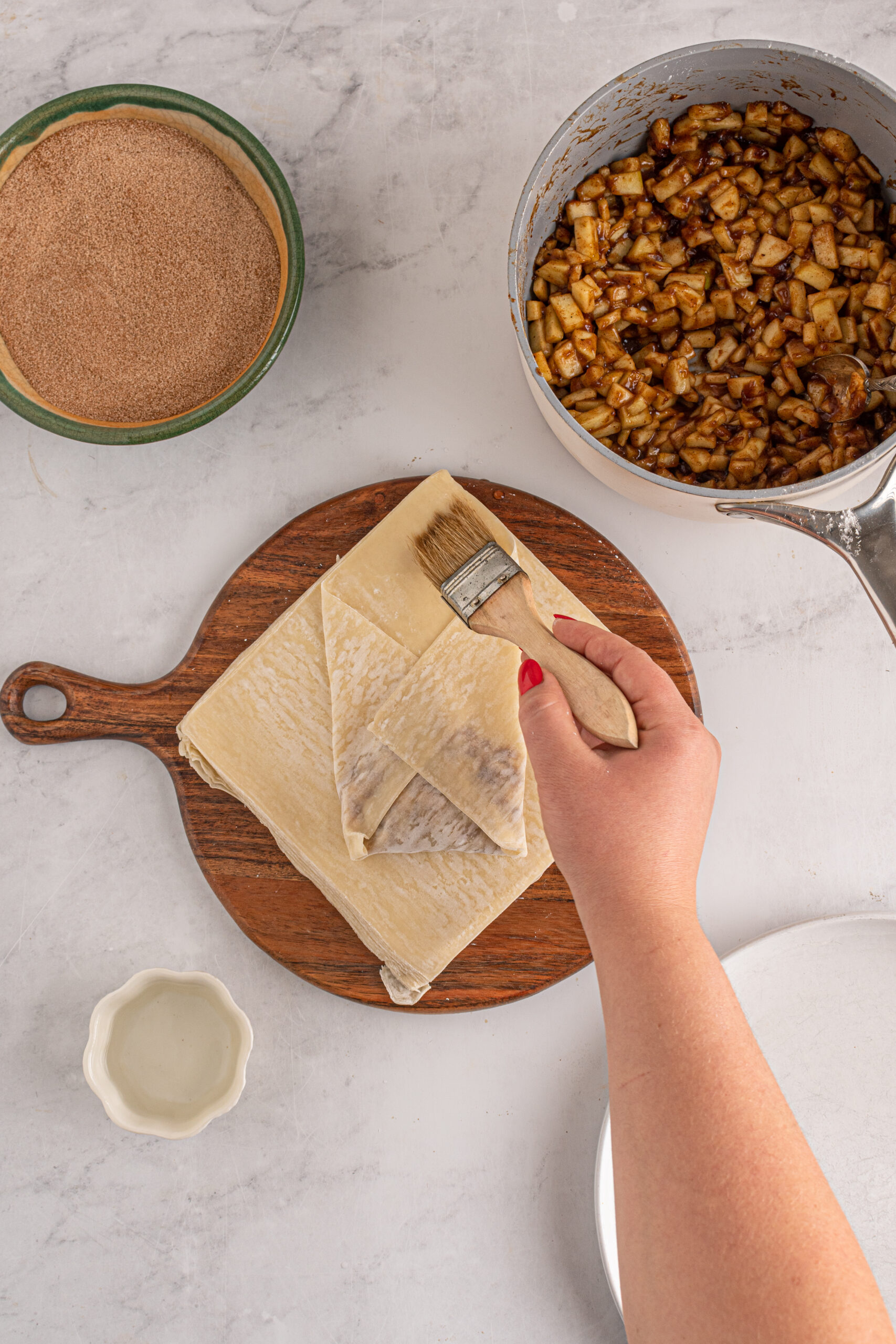 Overhead view of wrapping apple pie egg rolls.