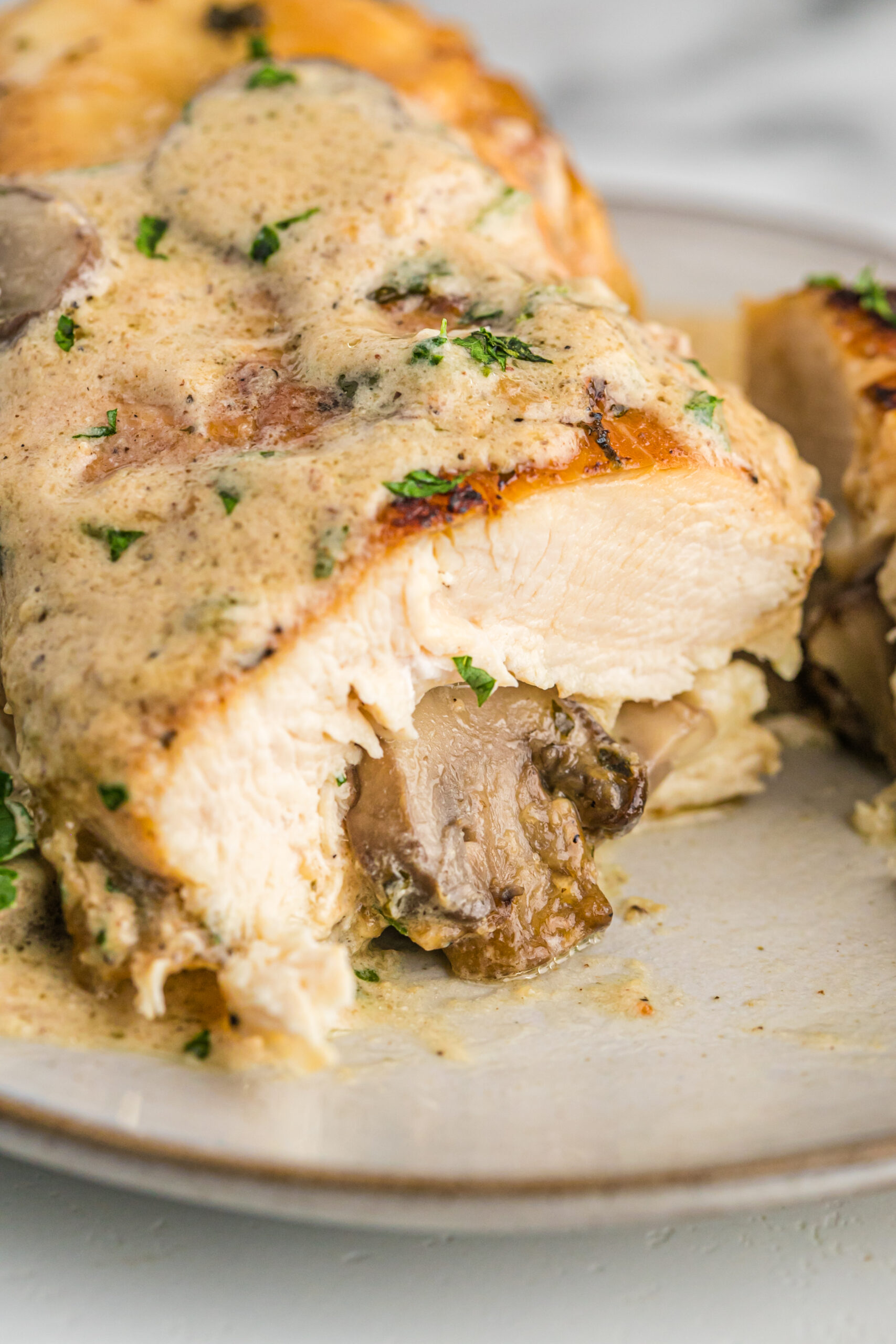 A close up piece of chicken cut in half showing the stuffing on the inside. 