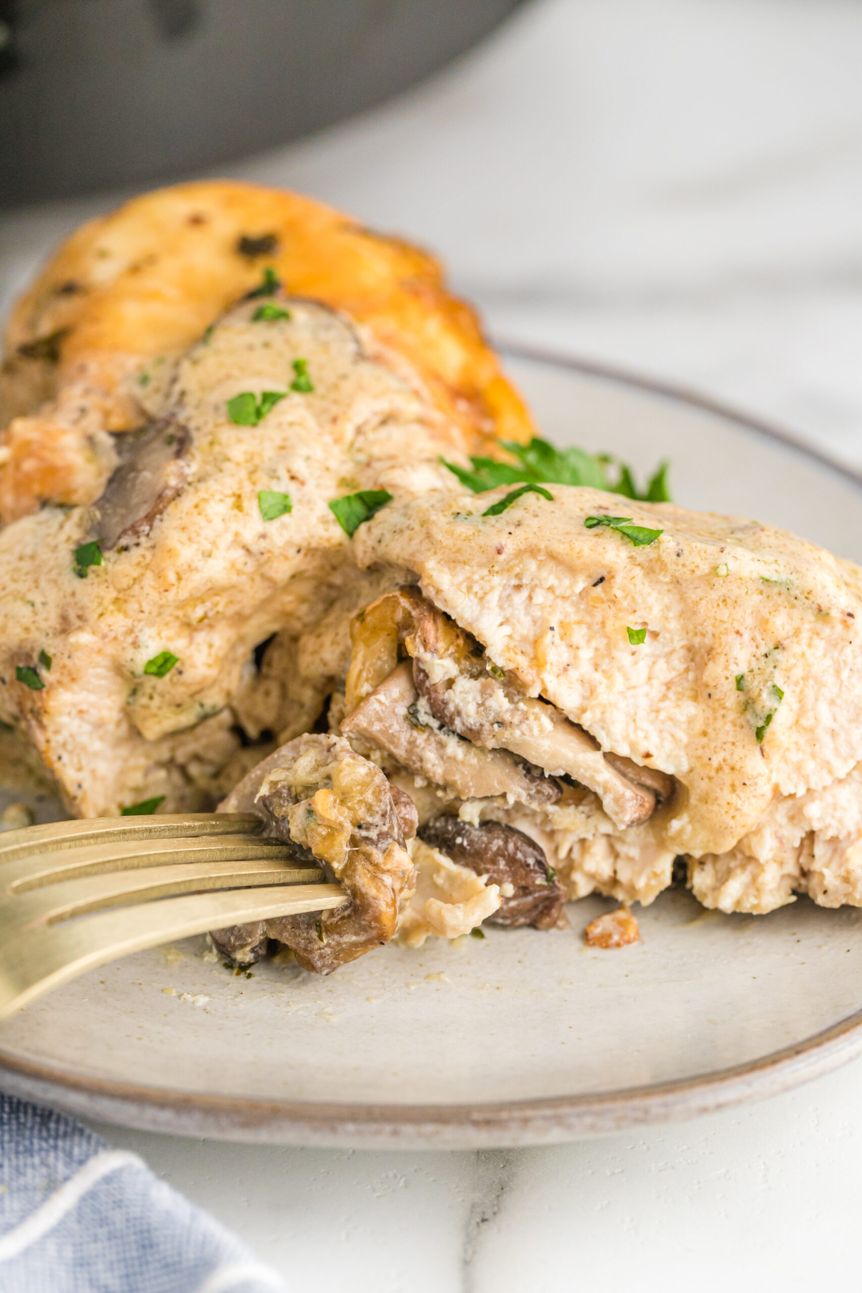 A close up piece of chicken cut in half showing the stuffing on the inside. 