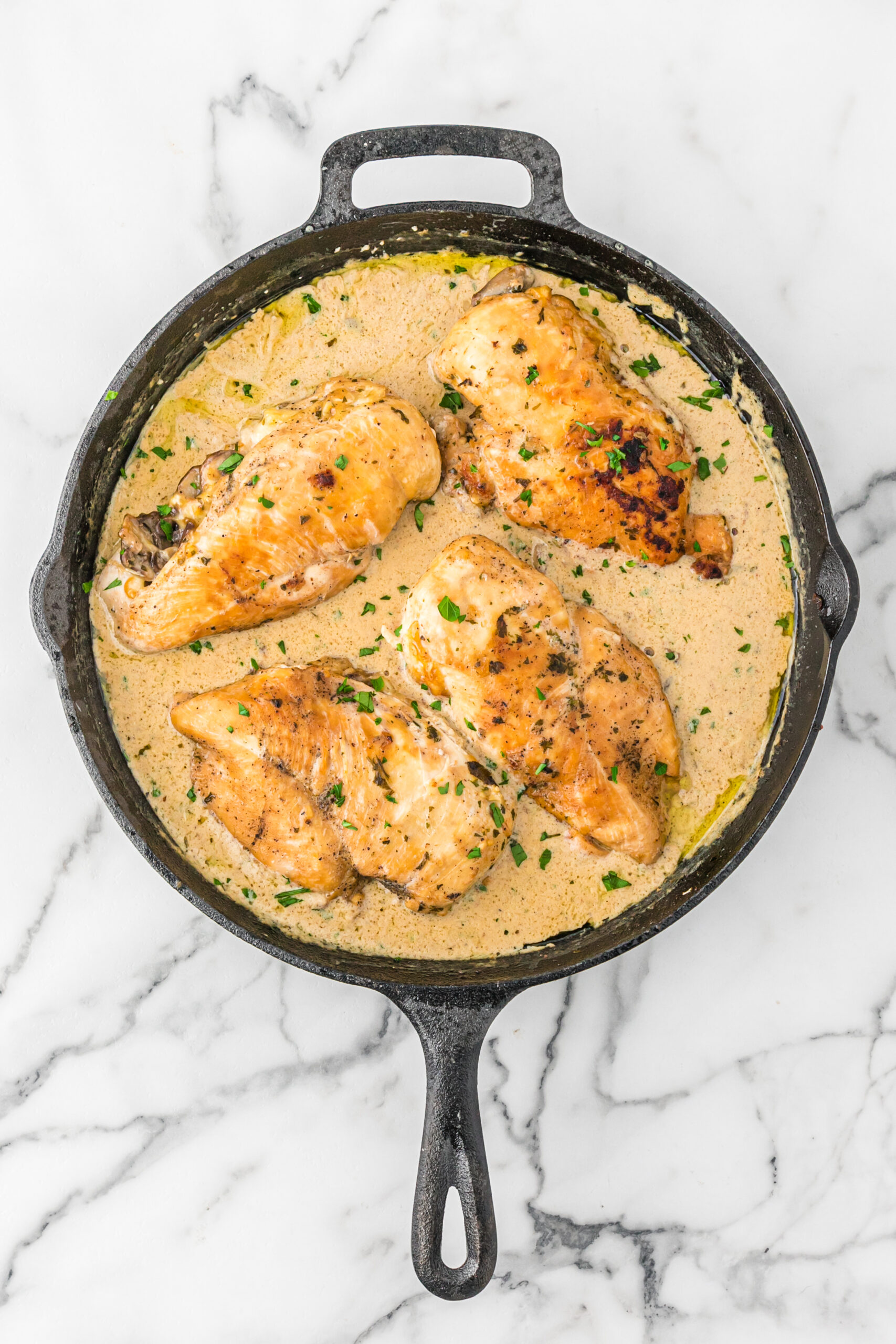 Overhead view of Cheesy Garlic Butter Mushroom Stuffed Chicken in a cast iron skillet. 