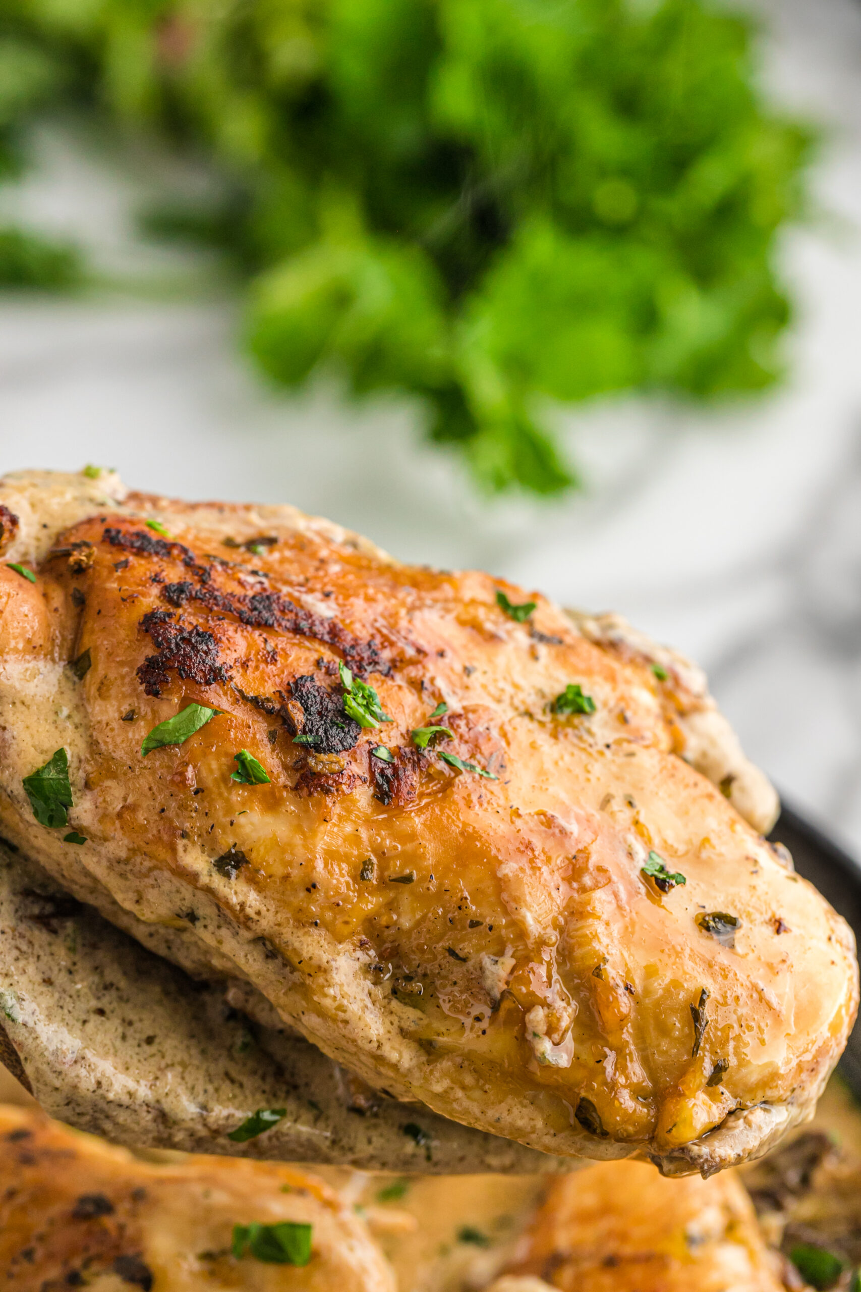 A piece of chicken being removed from the cast iron skillet using a wooden spatula. 