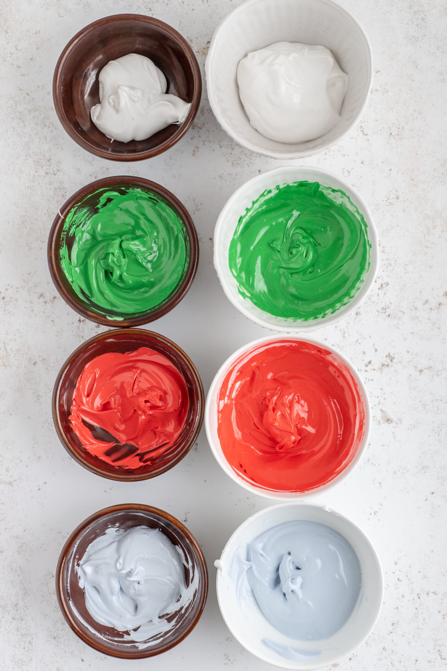 Above shot of the icing bowls with the red, green, and light blue food coloring mixed in.