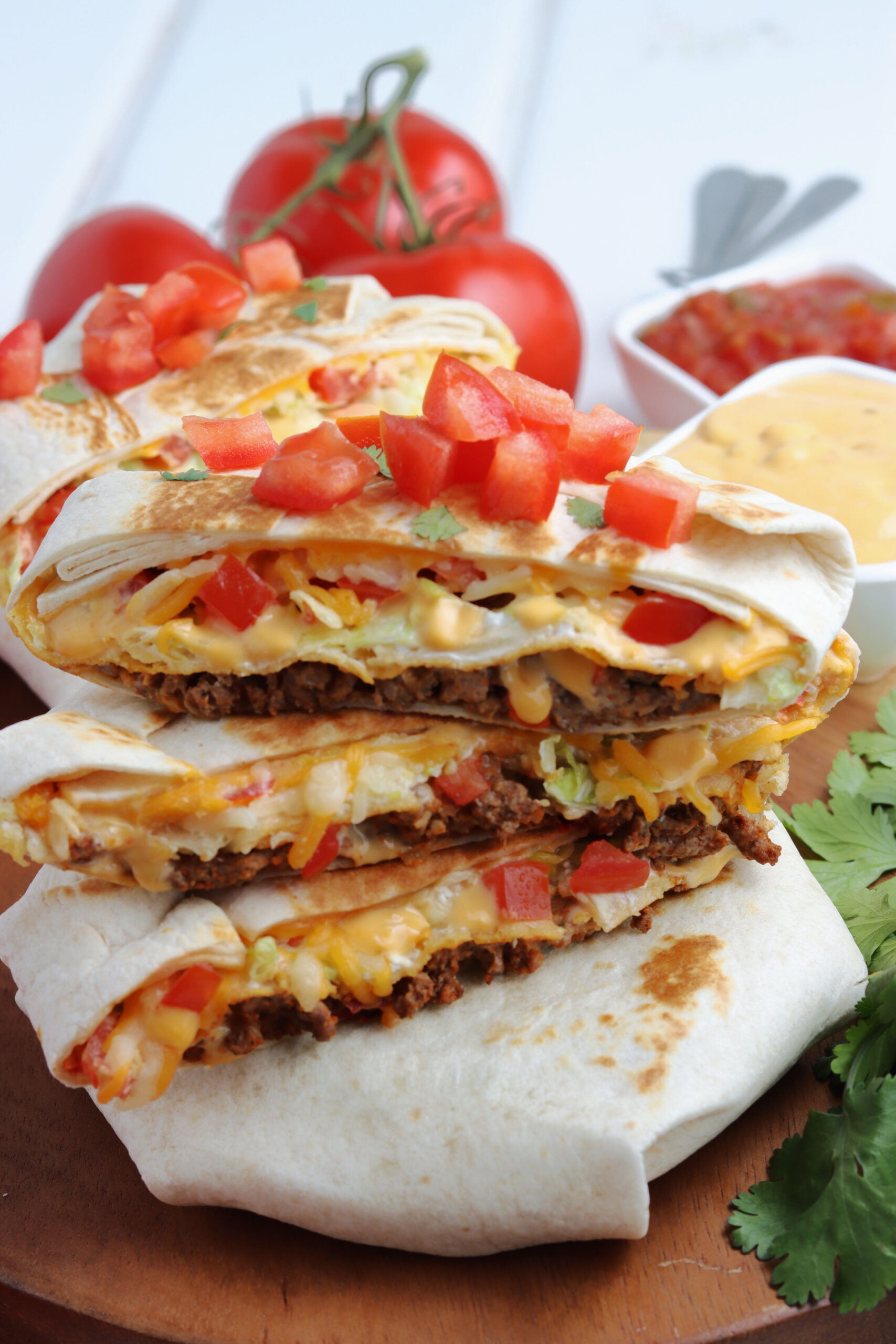 Three crunch wraps cut in half and stacked on top of each other showing the layers on the inside.