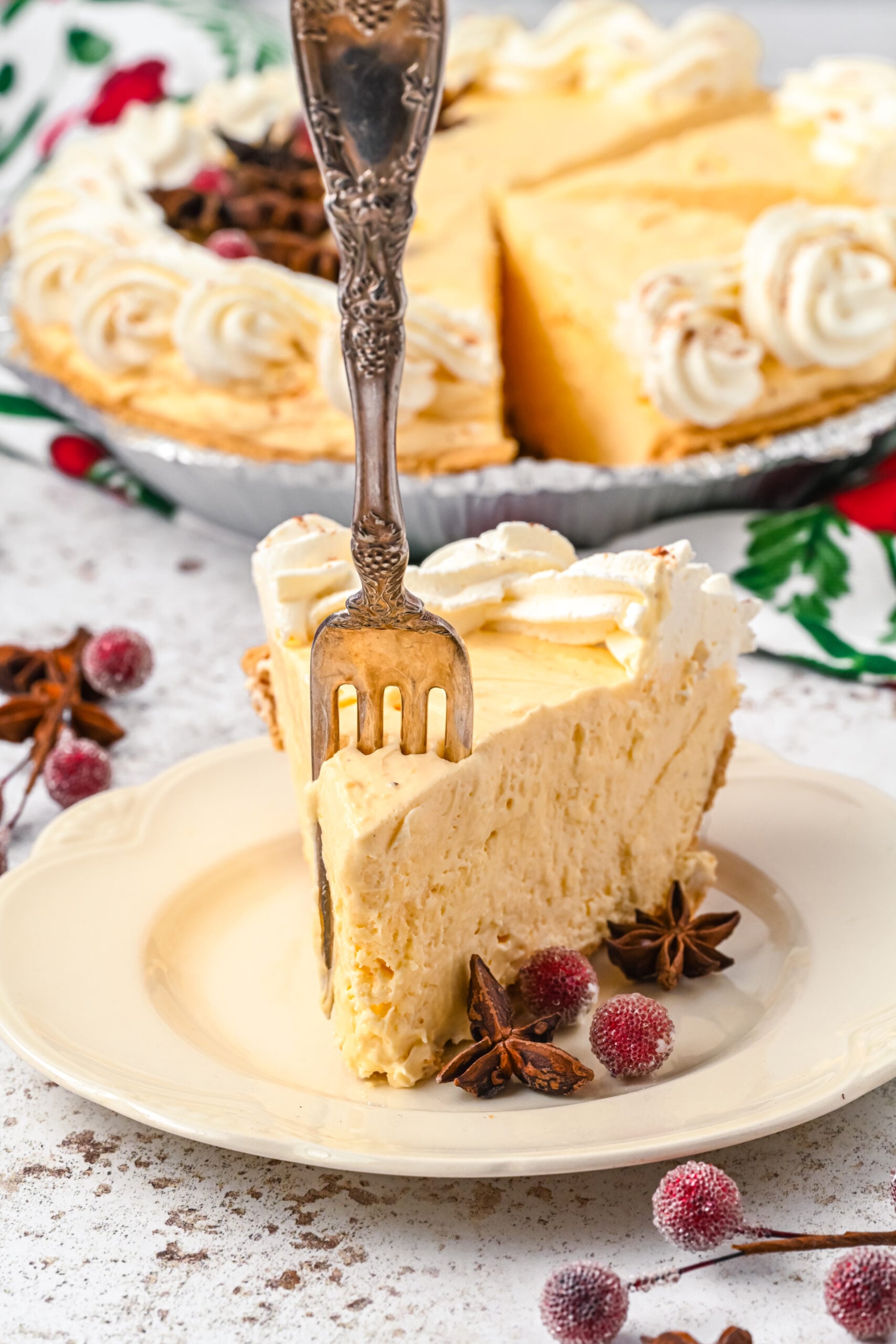 A piece of pie on a white dish with a silver fork removing a piece.