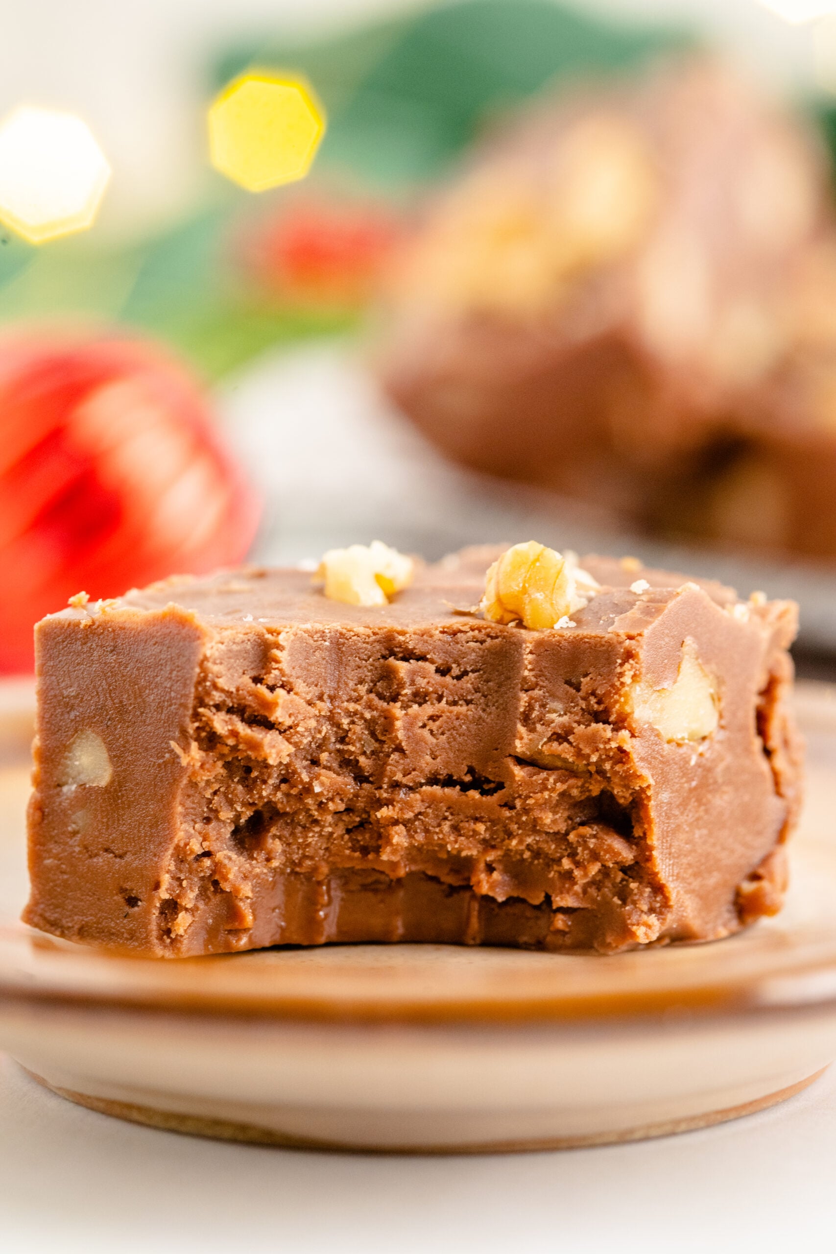 A piece of fantasy fudge on a brown plate with a bite removed showing the inside.