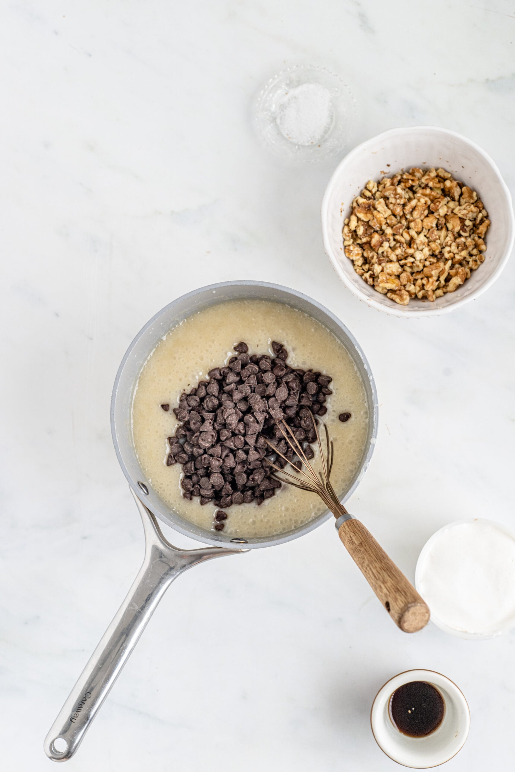 Overhead shot of ingredients melted in saucepan with chocolate chips poured on top.