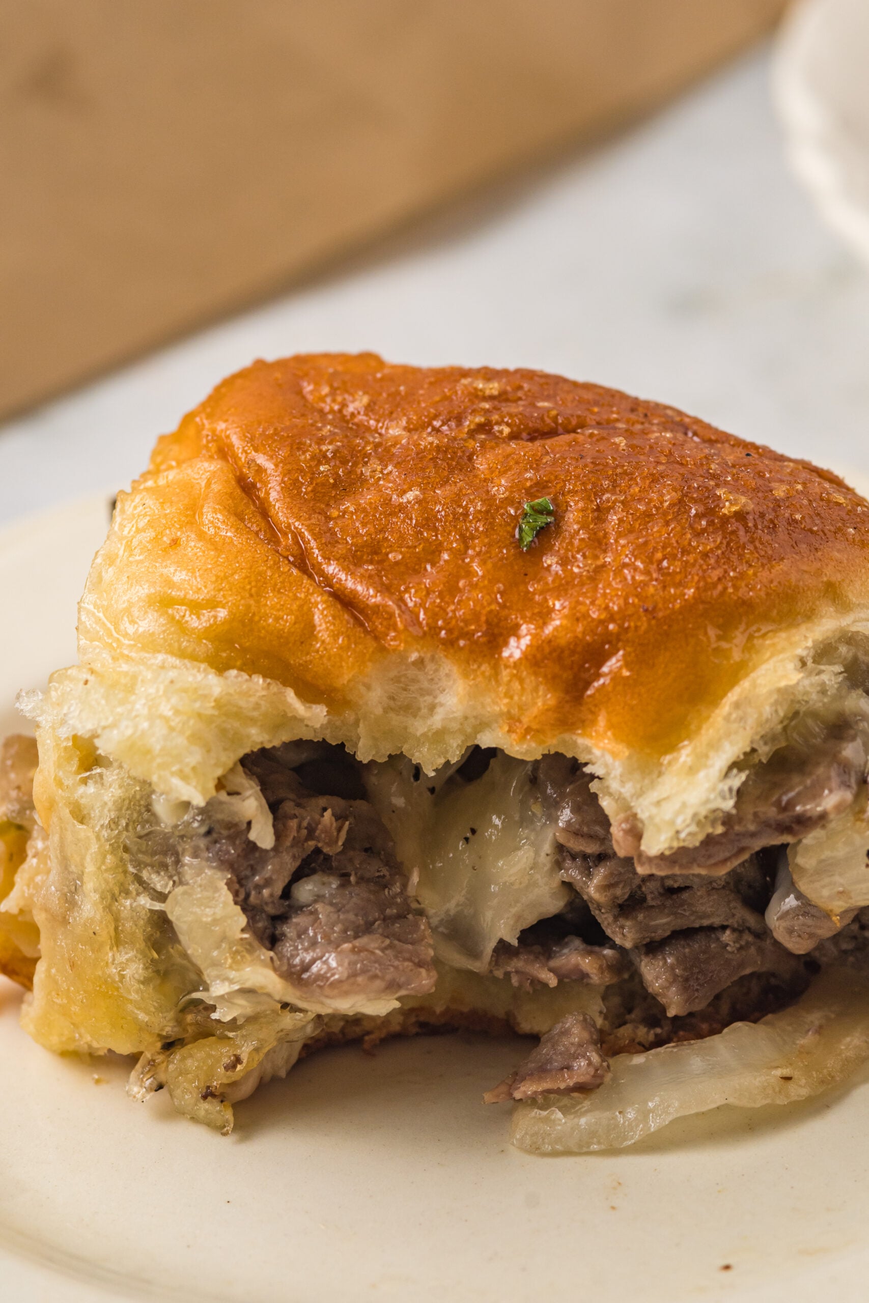 One slider on a white plate with a bite removed showing the inside. 