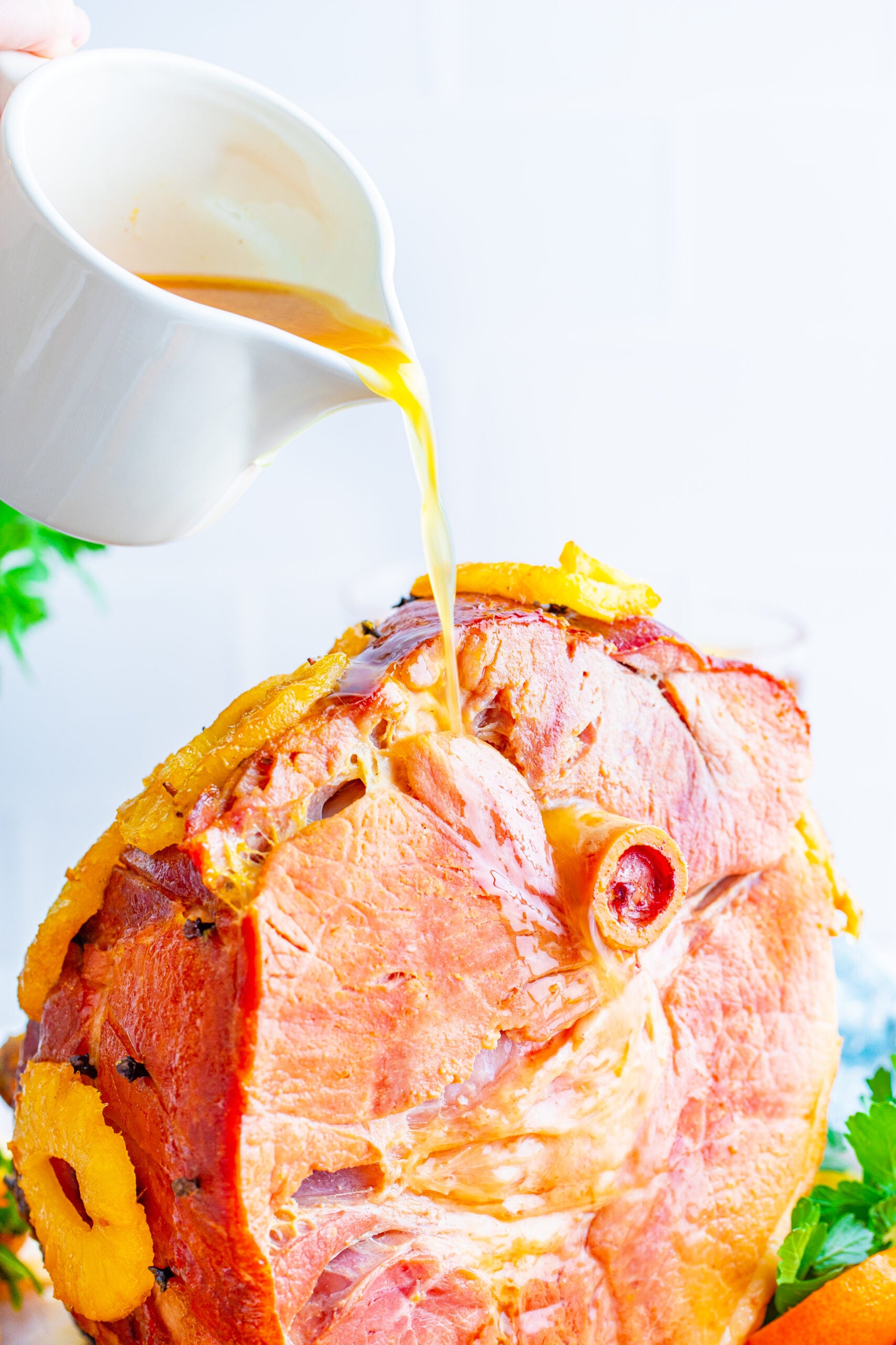 Pouring gravy over top of the finished baked ham.