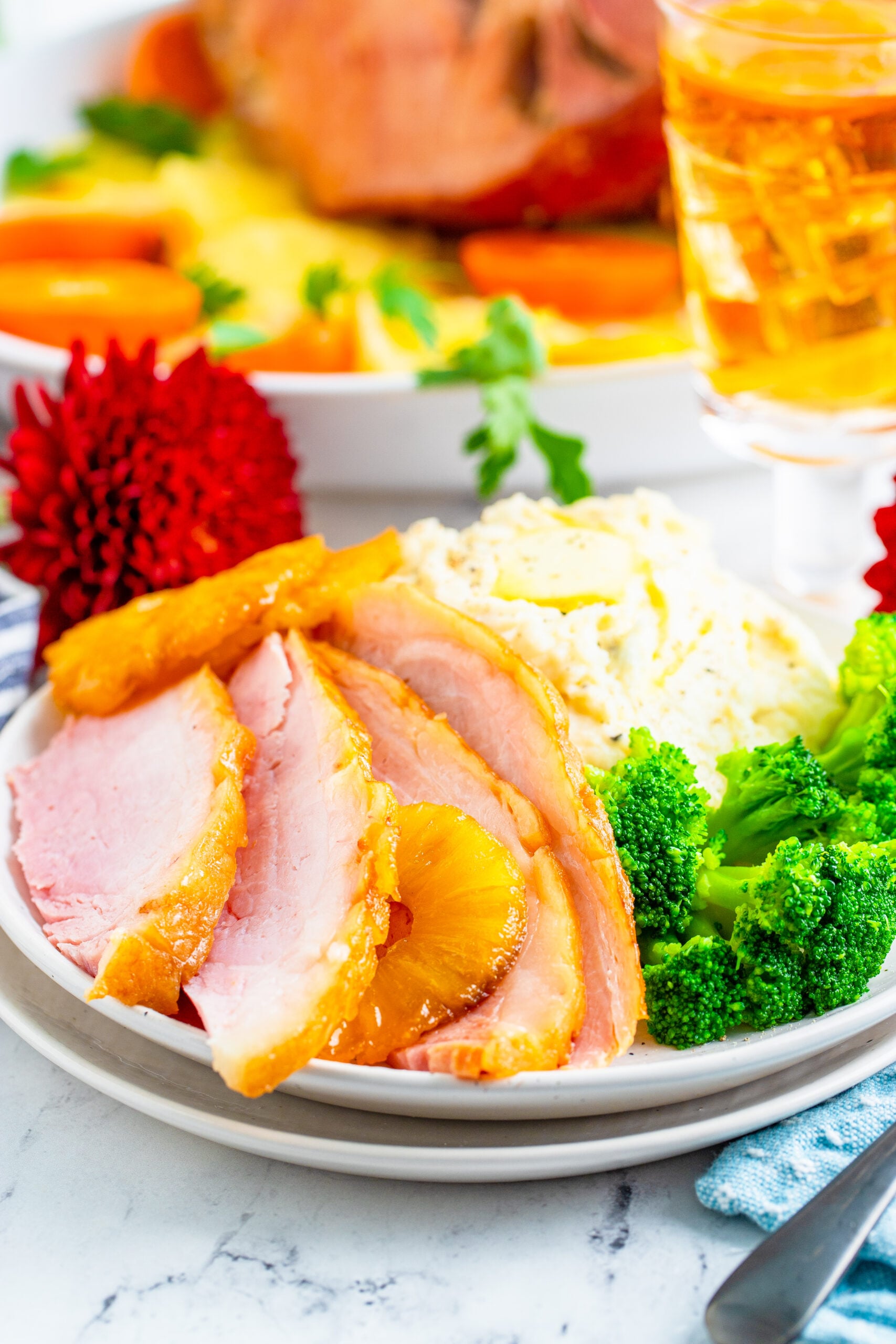 Slices of baked ham plated with broccoli and mashed potatoes.