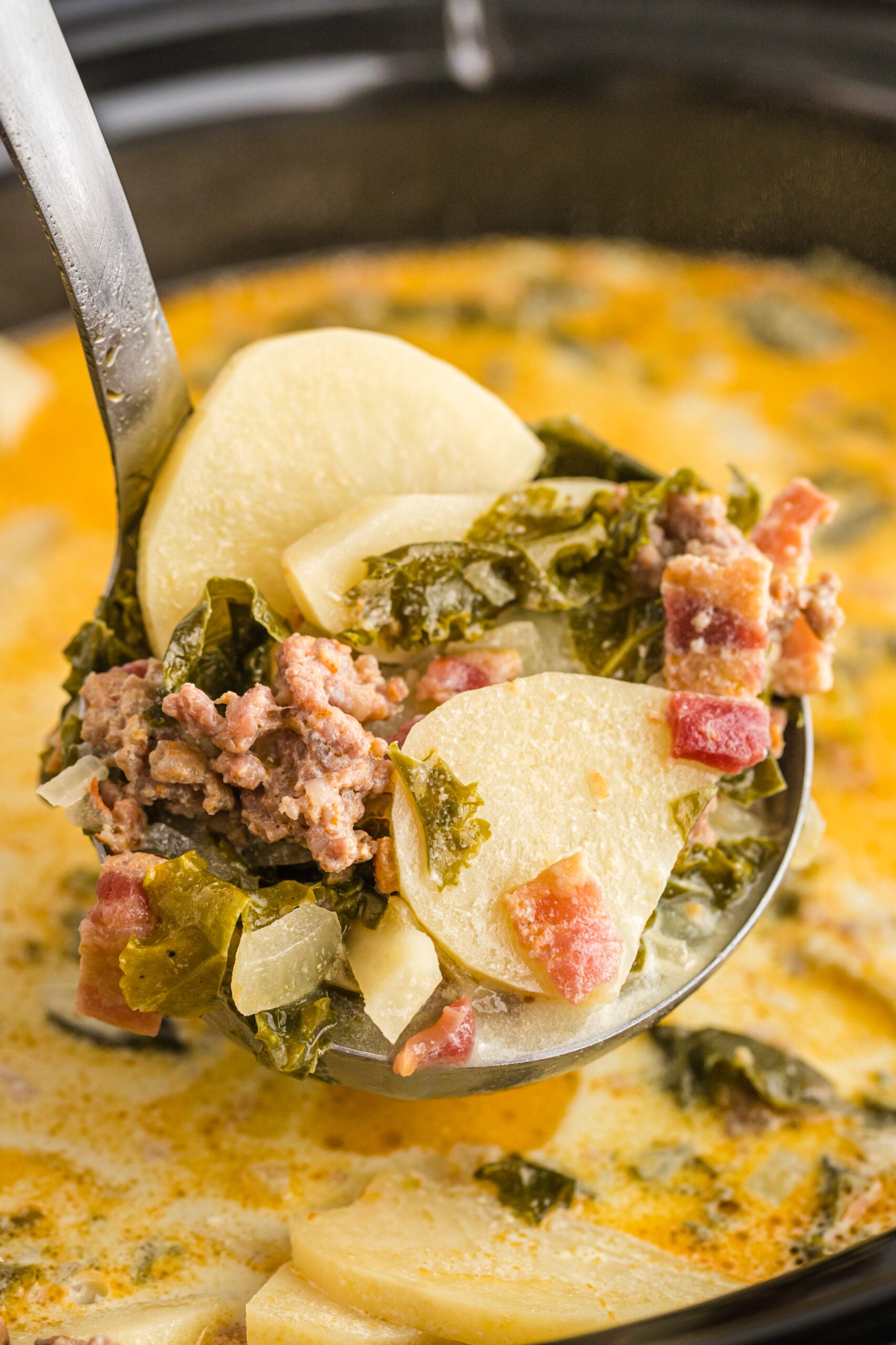 A silver ladle removing Zuppa Toscana Soup from the slow cooker.