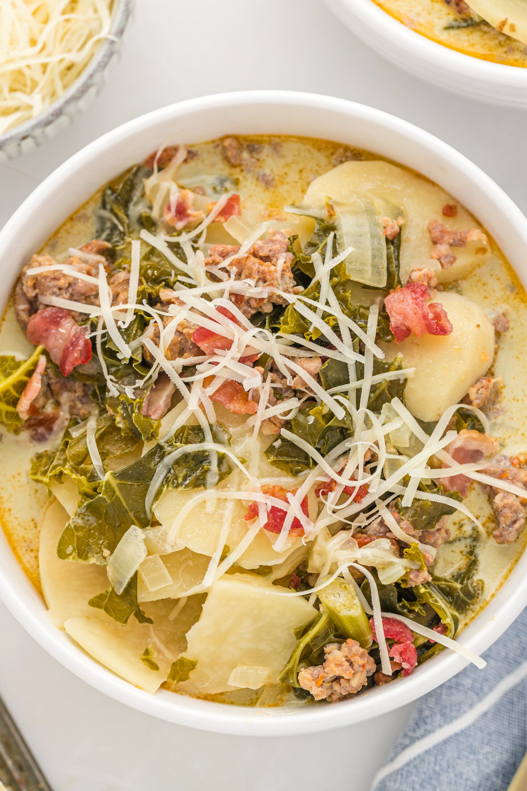 Overhead view of the soup in a white bowl topped with shredded cheese. 
