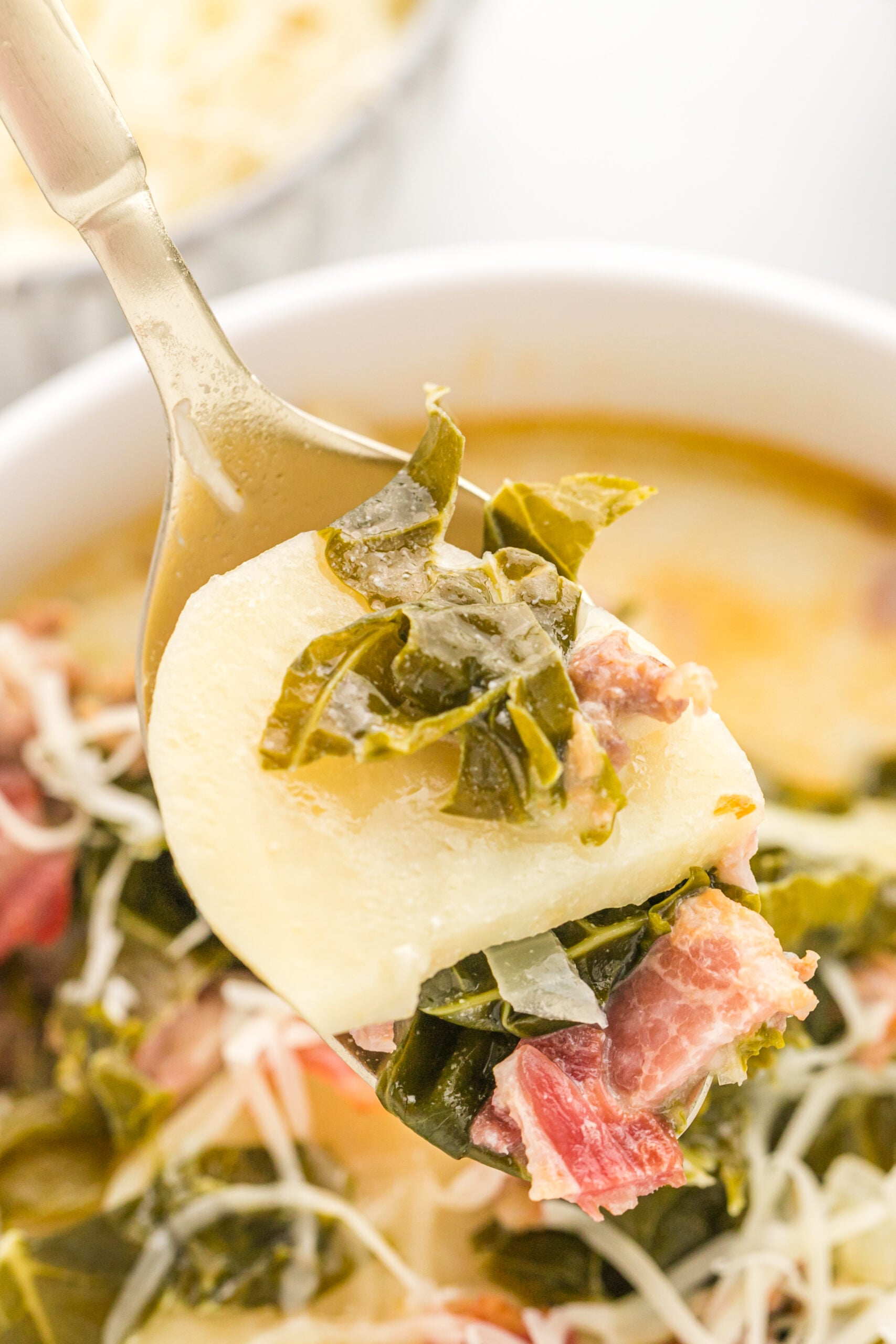 A gold spoon removing Zuppa Toscana Soup from the bowl. 