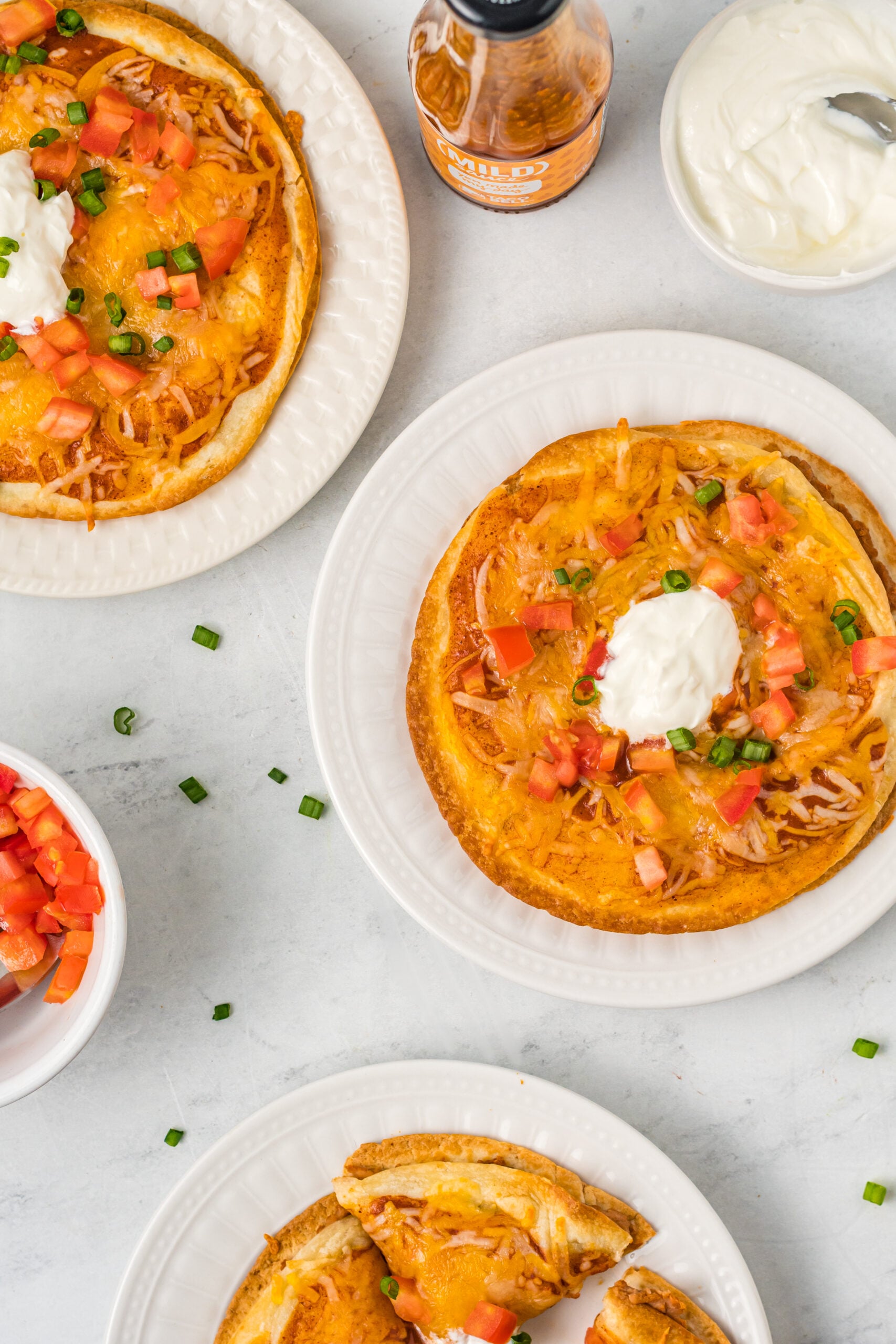 Overhead shot of three Mexican pizzas on white plates.