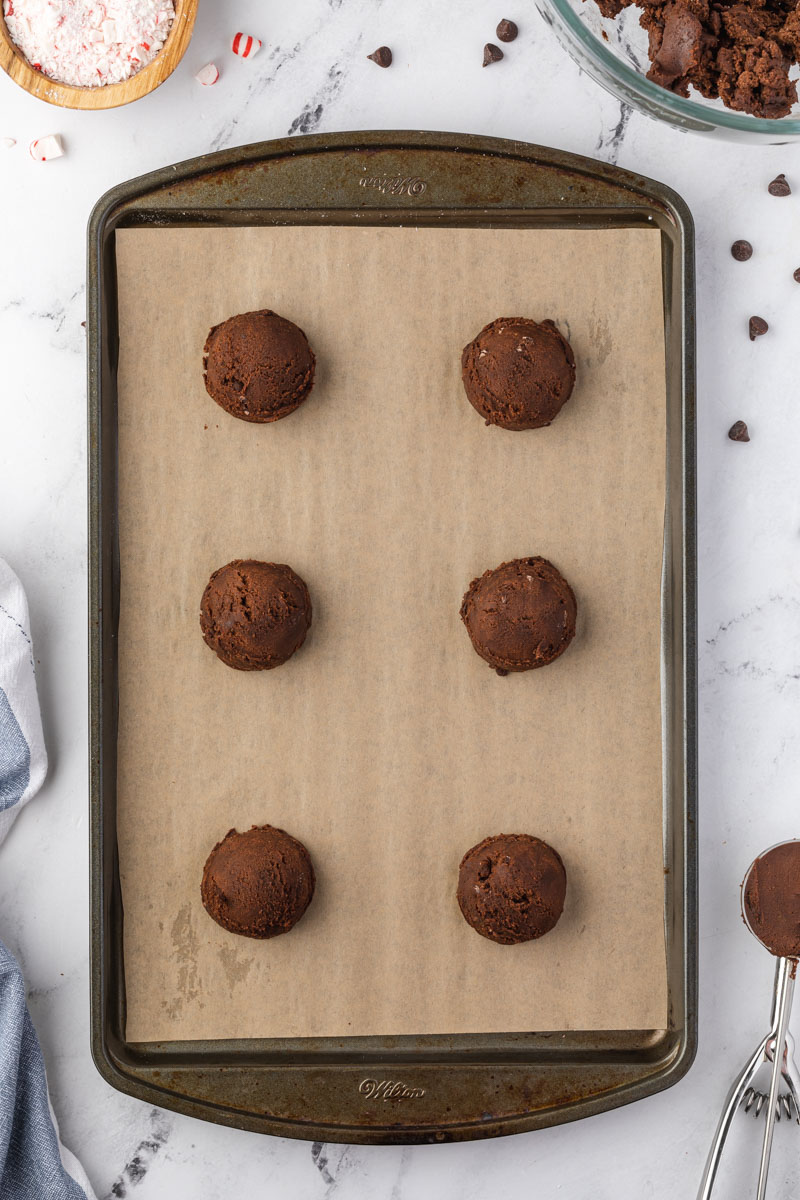 The cookie dough rolled out into balls on a baking sheet. 