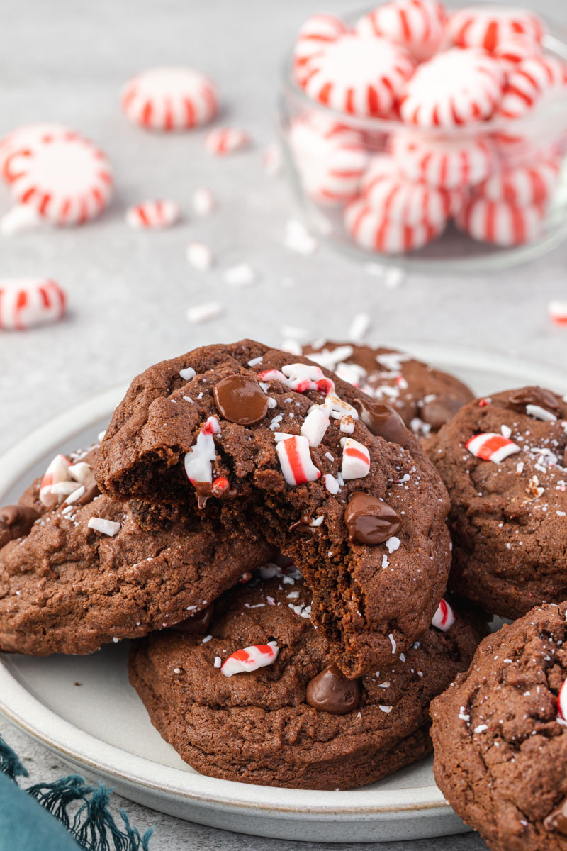 Double Chocolate Peppermint Cookies on a plate with a jar of peppermint candies in the background.