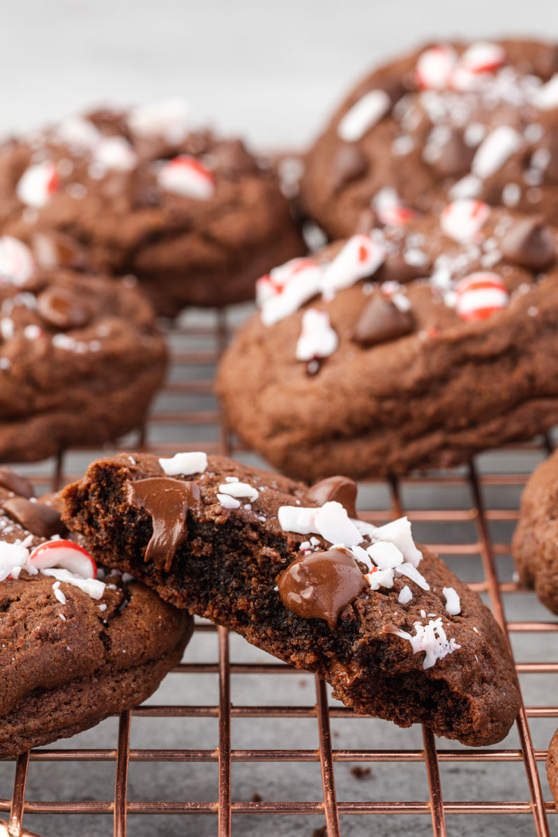 Chocolate Peppermint Cookie cut in half on a rose gold cooling rack showing the chewy inside of the cookie. 