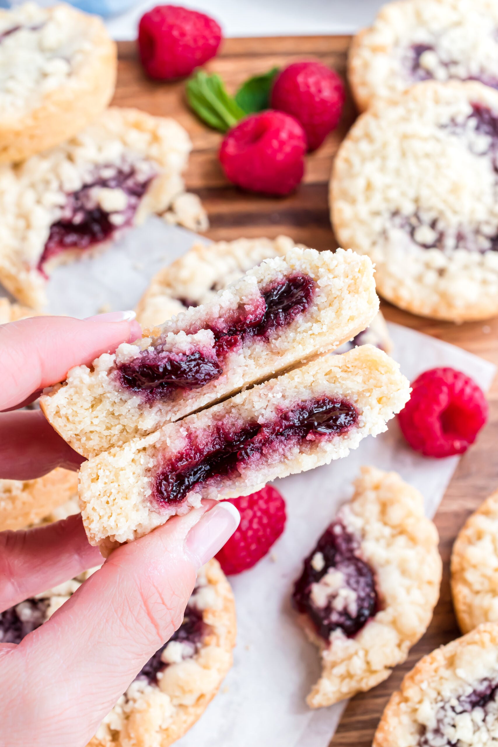 A raspberry cookie cut in half showing the raspberry filling center.
