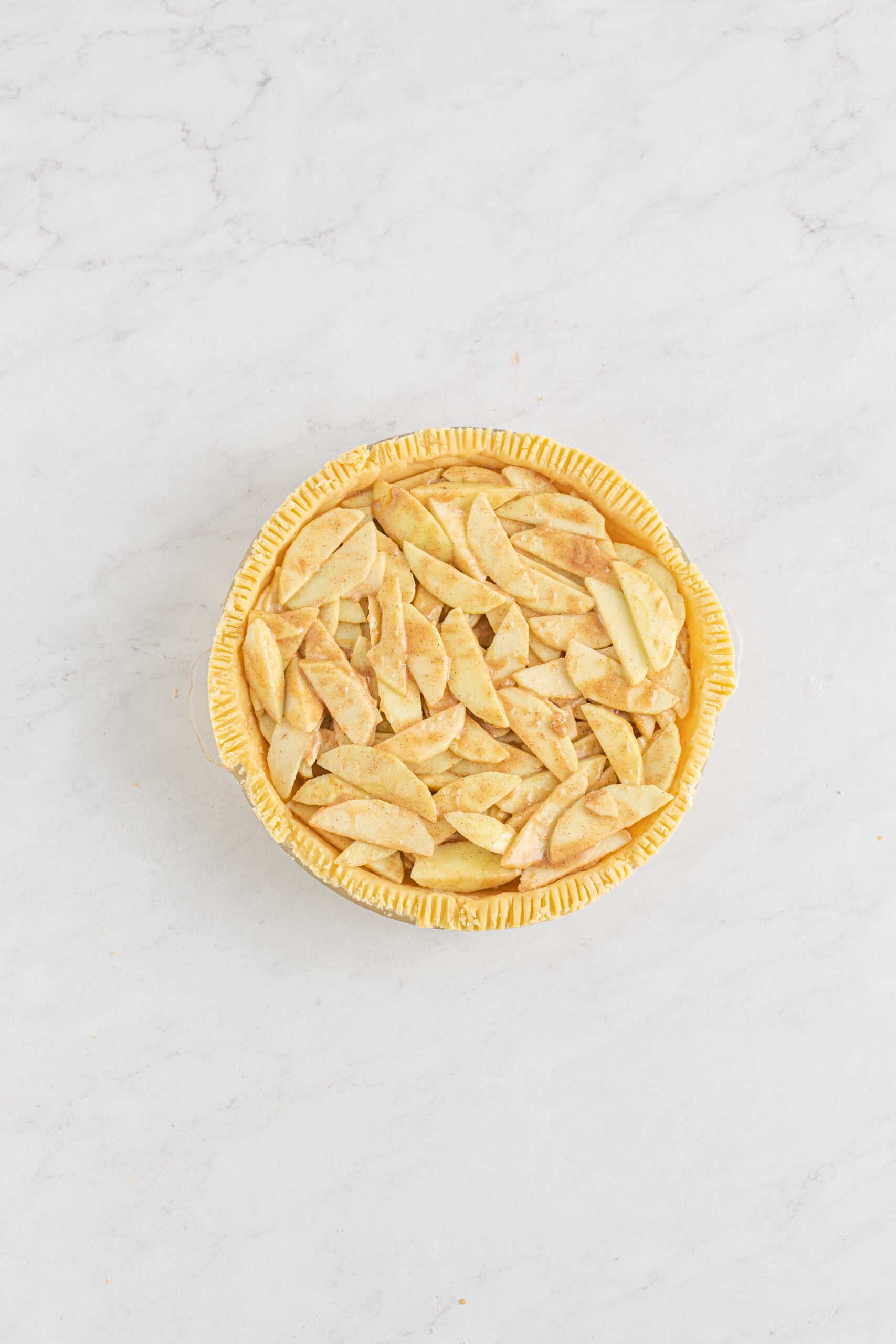 Overhead shot of the apples added into the unbaked crust. 