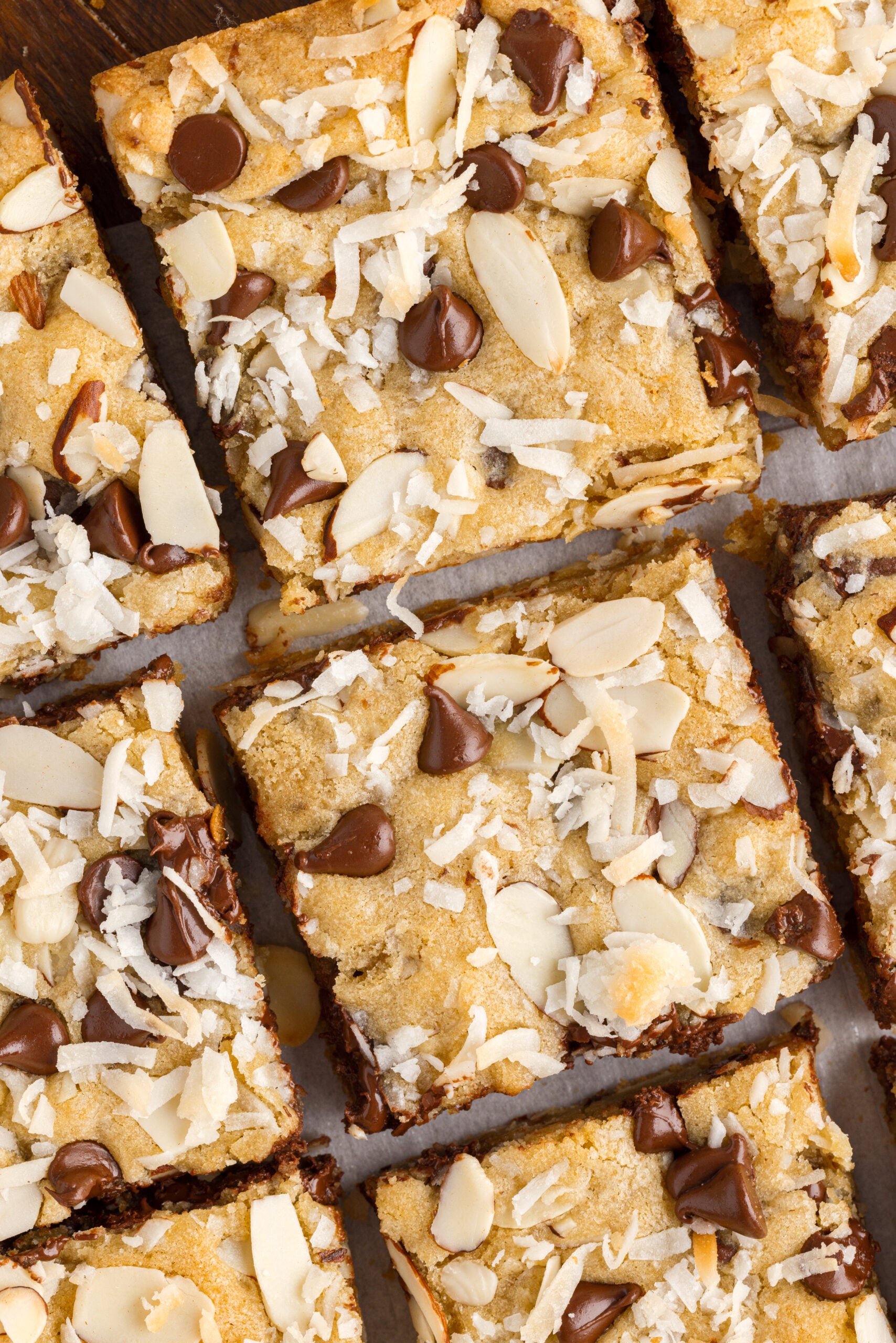 Overhead view of the almond joy cookie bars cut into pieces and topped with sliced almonds and chocolate chips.