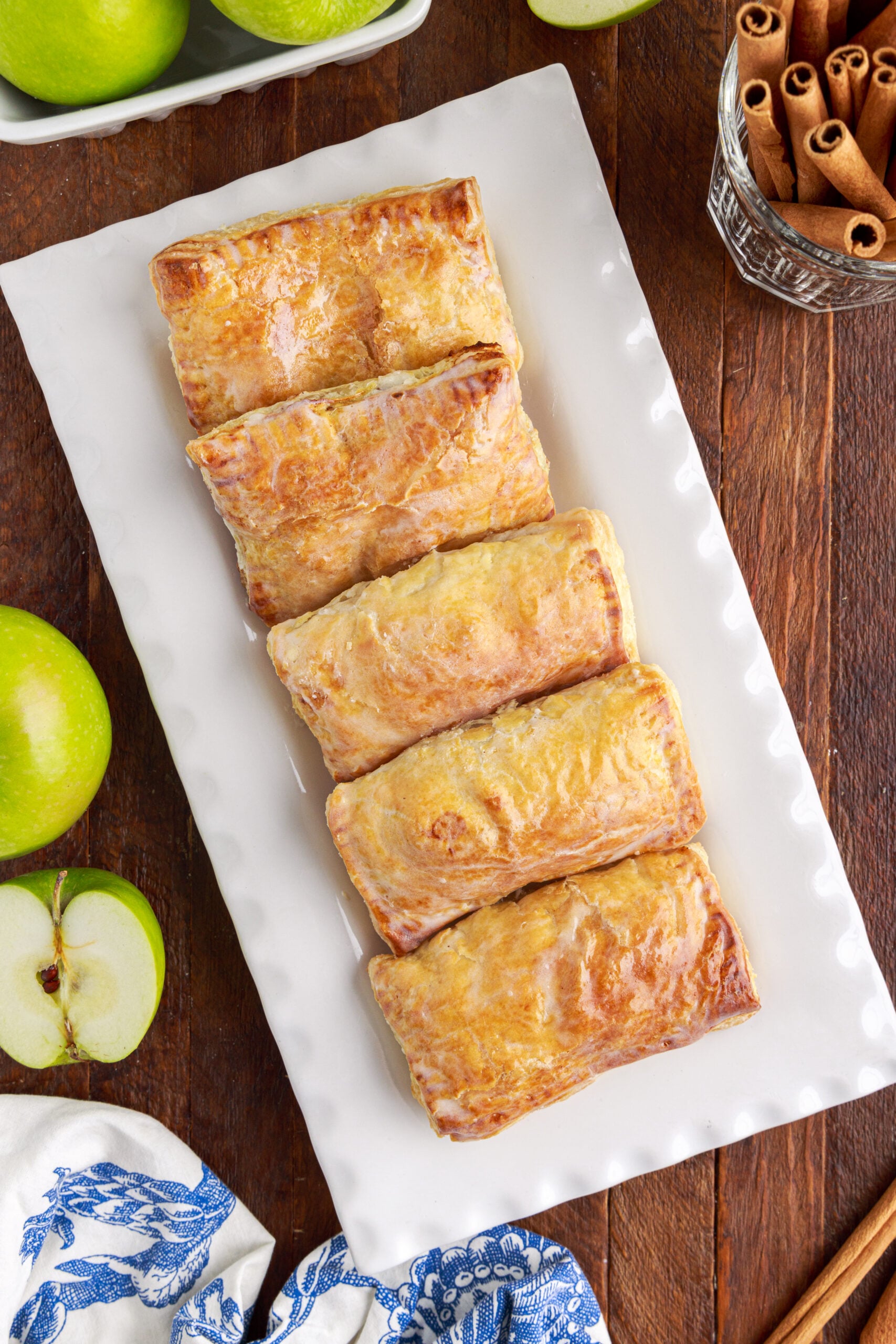 Overhead view of six apple hand pies on a white serving platter.