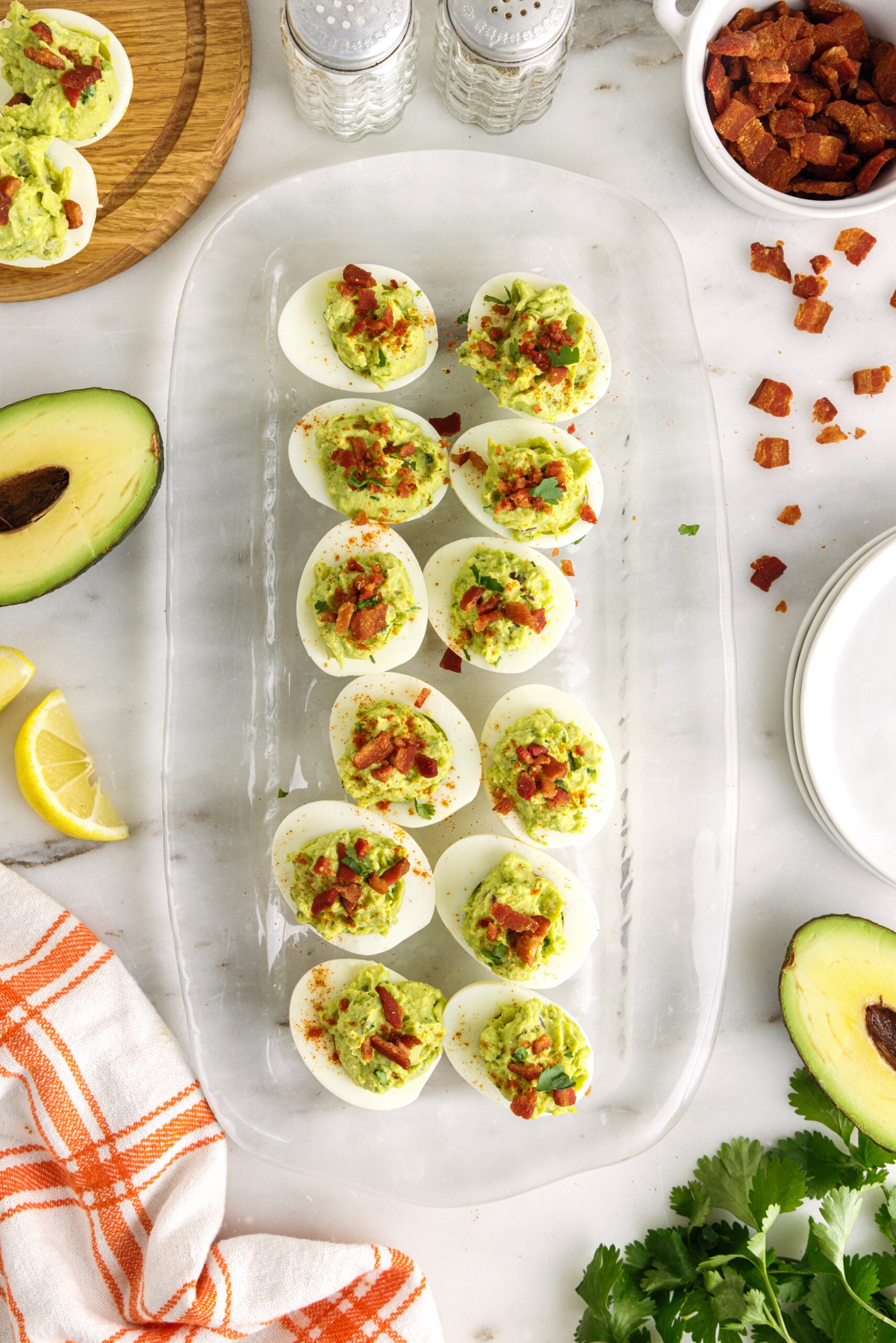Overhead shot of one dozen avocado deviled eggs on a clear serving tray.
