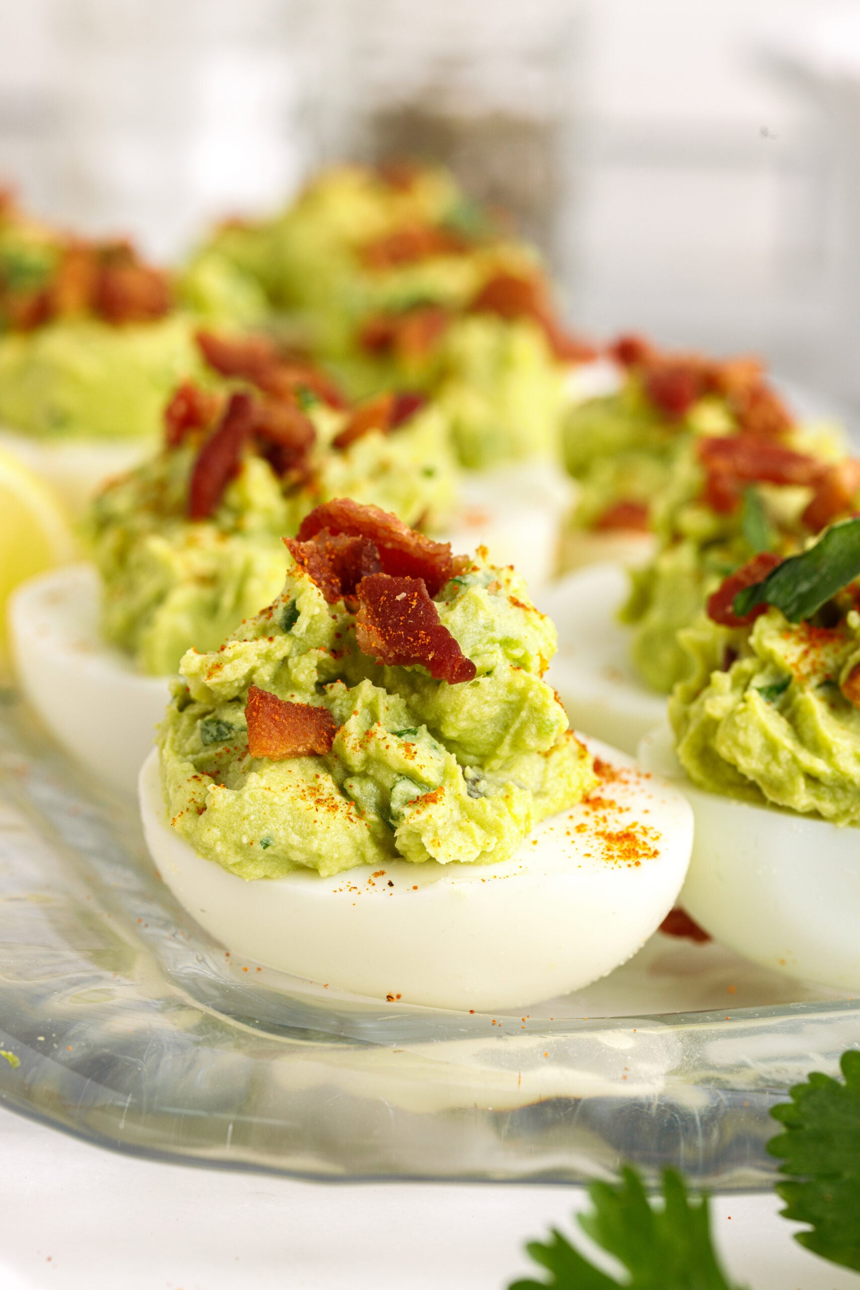 Side view of Avocado Deviled Eggs topped with chopped bacon.