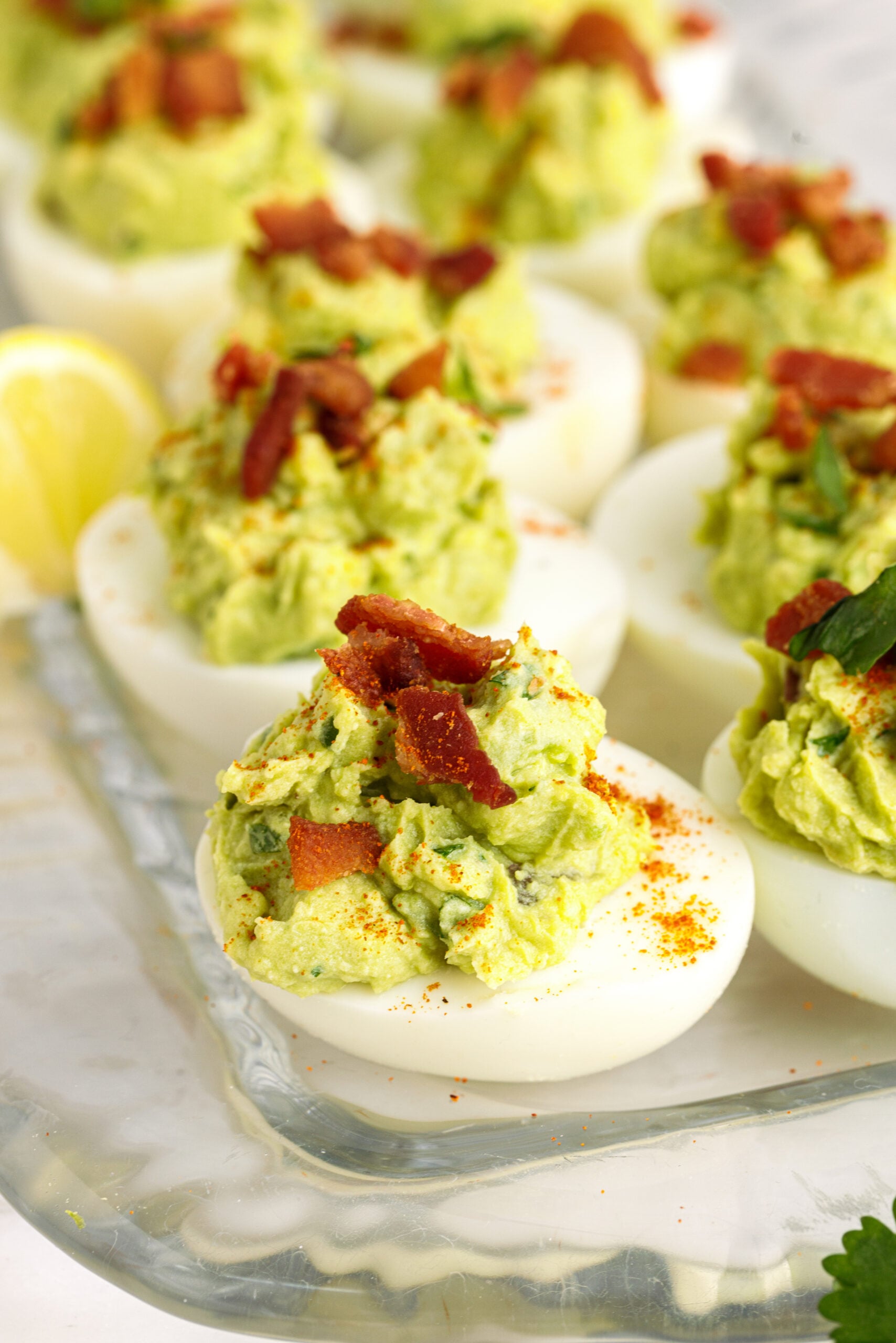 Side view of Avocado Deviled Eggs topped with chopped bacon.